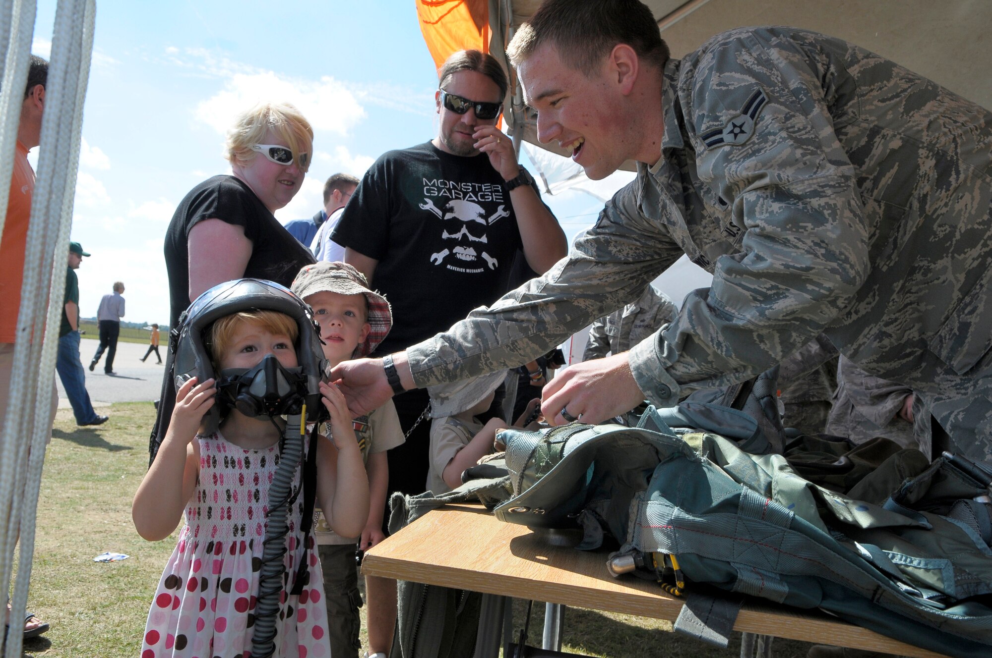 IMPERIAL WAR MUSEUM DUXFORD, England - Airman 1st Class Tyler Woodwick, 48th Operations Support Squadron aircrew flight equipment journeyman, helps 3-year-old Eleanor Marriage put on a HGU56-P pilot helmet during the Duxford American Air Day, Aug 19, 2011.  The American Air Day provided the local community the opportunity to see what Airmen stationed in England do on a daily basis.  The day included a mix of flying and ground-based activities that featured aircraft and personnel from RAFs Lakenheath and Mildenhall, which included F-15 and KC-135 flyovers.   (U.S. Air Force photo/Staff Sgt. Connor Estes)
