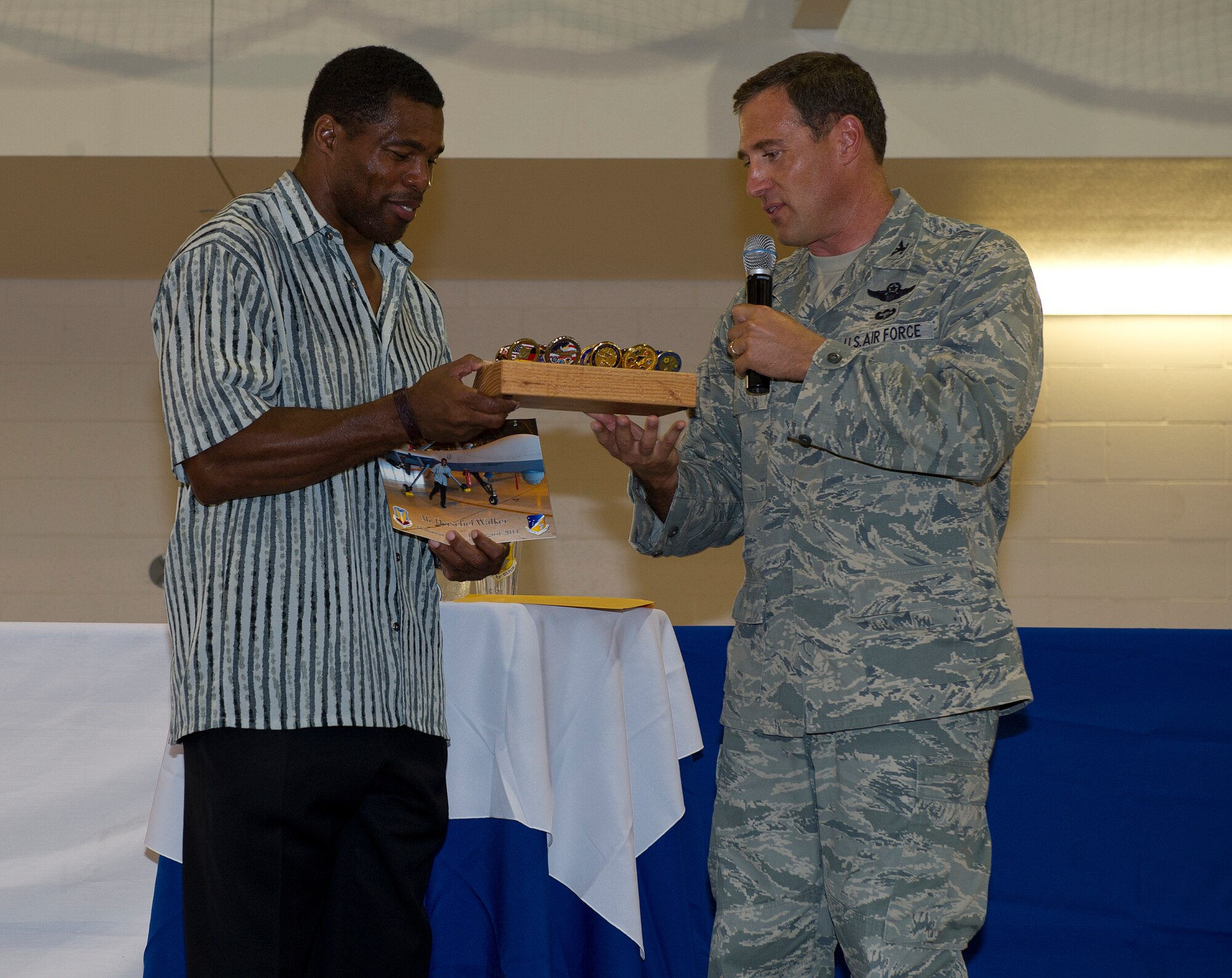 HOLLOMAN AIR FORCE BASE, N.M. -- U.S. Air Force Col. David Krumm, 49th Wing commander, presents Herschel Walker, former National Football League running back and current Strikeforce Mixed Martial Arts fighter, with coins from different squadrons of the 49th Wing and a photo taken of Walker in front of a MQ-9 Reaper from his tour of the 29th Attack Squadron Aug. 19, 2011, at the Domenici Fitness and Sports Center. The gifts were presented to Walker as a thank you for his time spent visiting the base and talking to the Airmen about his life and how he was able to persevere through the struggle of having dissociative identity disorder. (U.S. Air Force photo by Senior Airman DeAndre Curtiss/Released)