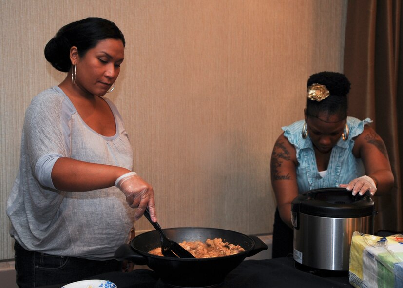 MINOT AIR FORCE BASE, N.D. -- Master Sgt. Camille Stamatakos (left), 5th Medical Support Squadron Tri-Care operations and patient administration flight chief, and Staff Sgt. Nyckisha Jones, 5th Force Support Squadron readiness and training non-commissioned officer, prepare curry chicken at the Jimmy Doolittle Center Aug. 19. Participants of the event prepared a variety of international dishes for attendees to experience. The event ran for approximately five hours and included a variety of multi-cultural booths, cooking, dancing, singing, and poetry. (U.S. Air Force photo/Senior Airman Ashley N. Avecilla) (RELEASED)