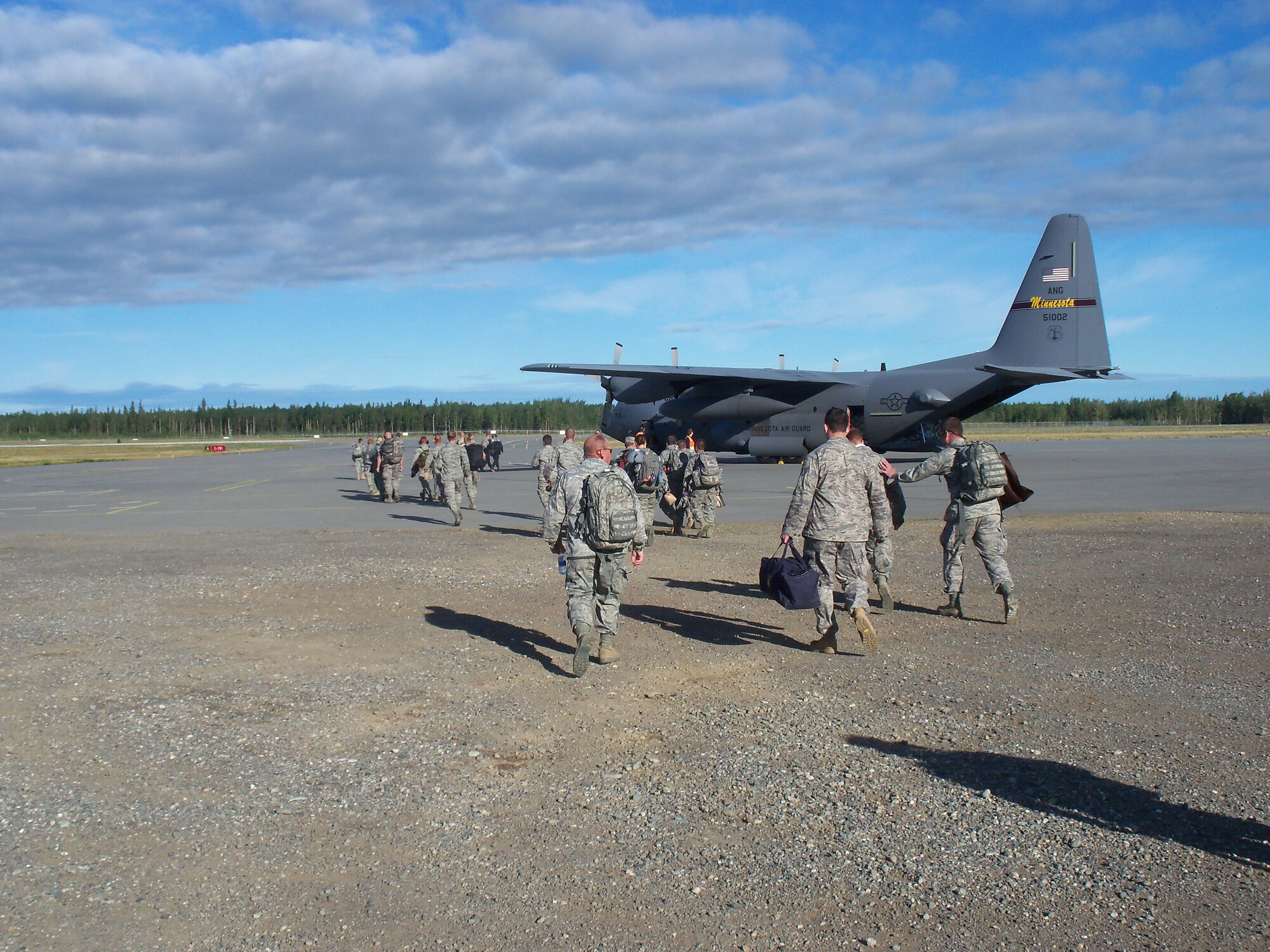 Members of the148th Fighter Wing Civil Engineering and Services Squadrons cross a flightline at Fort Greely, Delta Junction, Alaska July 23, 2011 after spending two weeks constructing training facilities. The civil engineers built a simulated village and a live-fire facility--an effort that required more than 3,000 hours of labor.