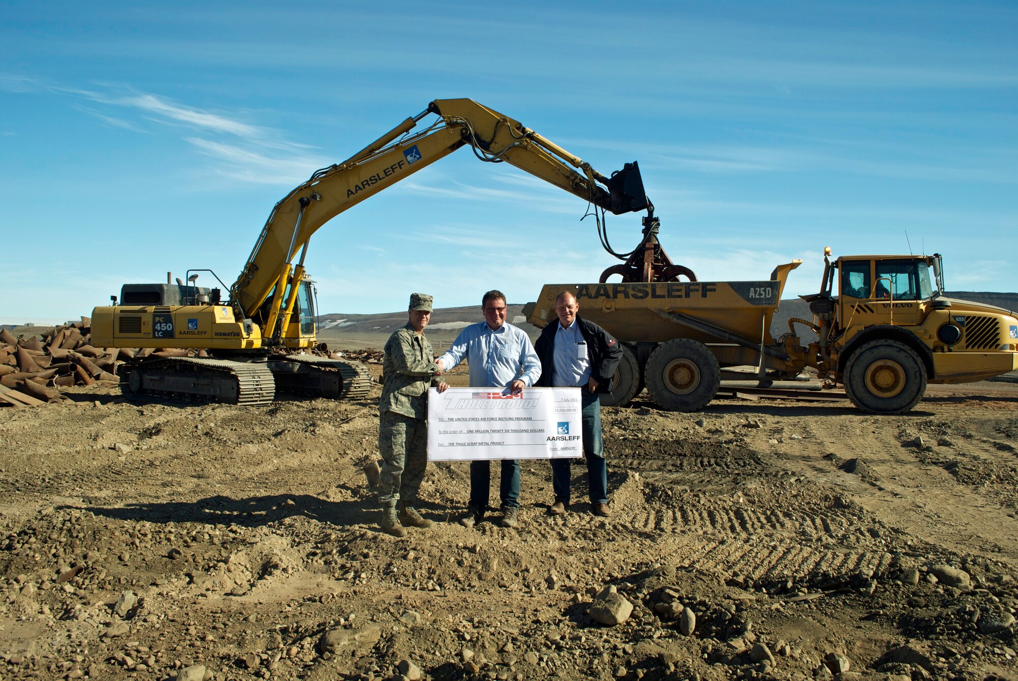 Col. Mark Allen (left), former Thule Air Base commander, receives a check for more than $1 million from Torsten Thygesen (center), Aarsleff senior project manager, and Peter Riggelsen, Rimeco recycling company. The money was proceeds from a 15,000-ton scrap metal pile that had accumulated during the past 15 years at Thule AB. (U.S. Air Force photo/Master Sgt. Jocelin Borisow) 