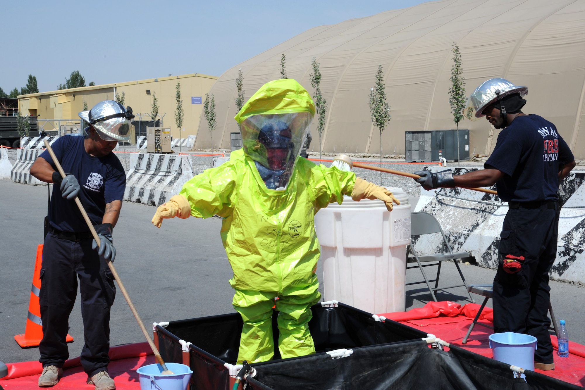 Firefighters scrub Kyrgyz Maj. Zapira Shamuratora’s chemical protection after she responded to a suspicious package scenario during a bilateral information exchange at the Transit Center at Manas, Kyrgyzstan, Aug. 19. Shamuratora is the Ministry of Emergency Services chemical, biological, radiological, nuclear and high-yield explosives squadron chief. (U.S. Air Force photo/Tech. Sgt. Hank Hoegen)