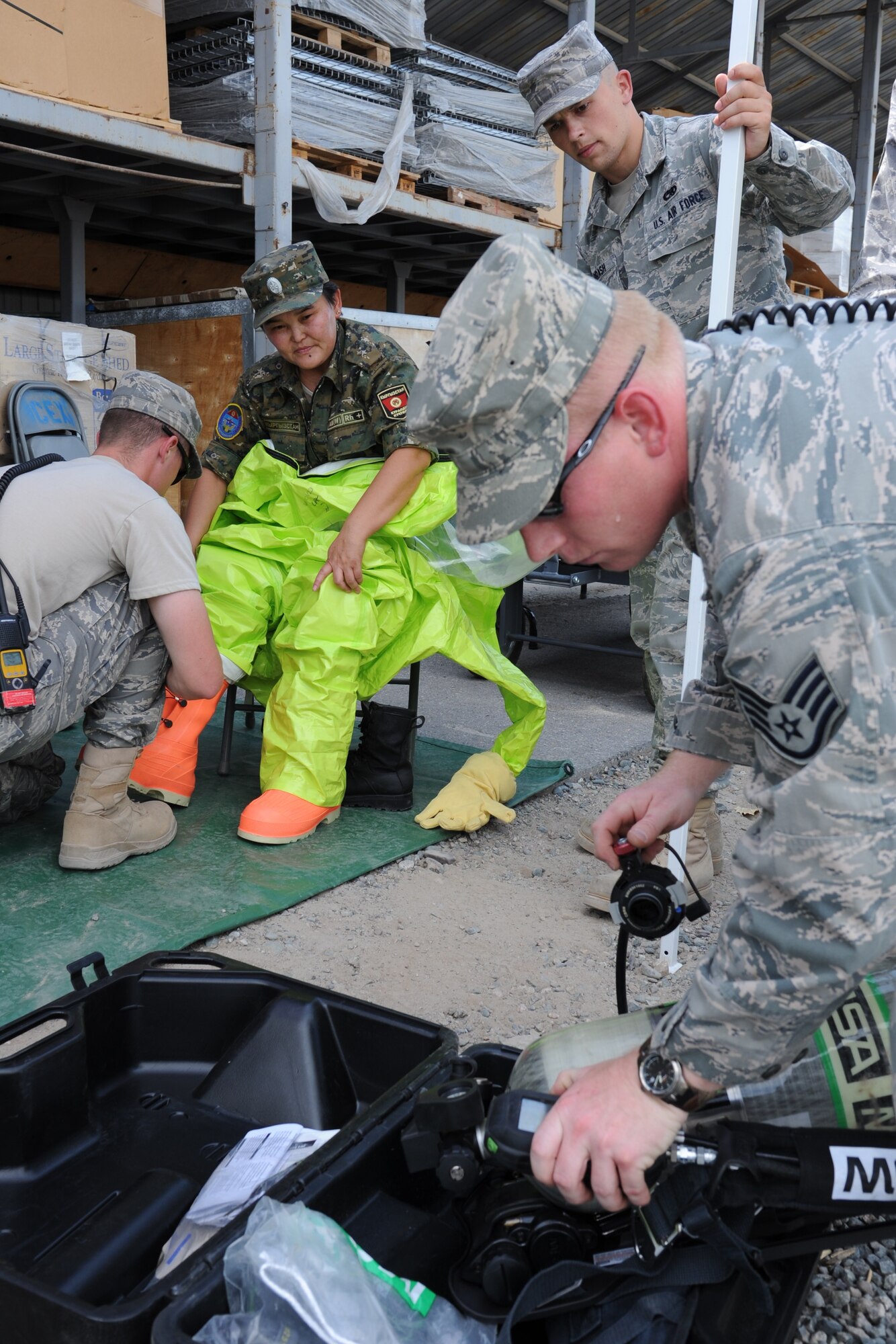 Emergency response Airmen help Kyrgyz Maj. Zapira Shamuratora don a chemical protection suit during a bilateral information exchange at the Transit Center at Manas, Kyrgyzstan, Aug. 19. Shamuratora is the Ministry of Emergency Services chemical, biological, radiological, nuclear and high-yield explosives squadron chief. (U.S. Air Force photo/Tech. Sgt. Hank Hoegen)