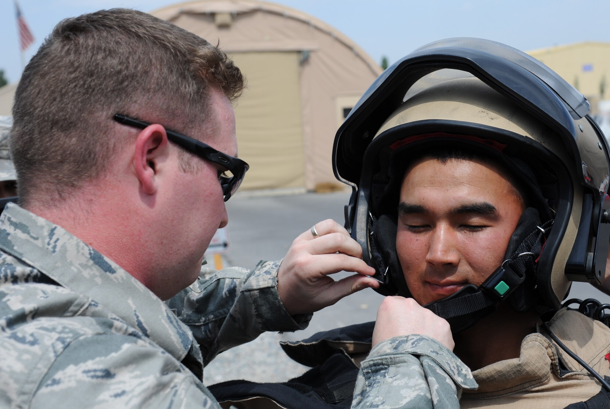 Staff Sgt. Paul Pest helps a Kyrgyz Republic soldier and fellow explosive ordnance disposal technician don a bomb suit during a bilateral information exchange at the Transit Center at Manas, Kyrgyzstan, Aug. 19. Pest is deployed to the 376th Expeditionary Civil Engineer Squadron from Seymour Johnson Air Force Base, N.C. (U.S. Air Force photo/Tech. Sgt. Hank Hoegen)
