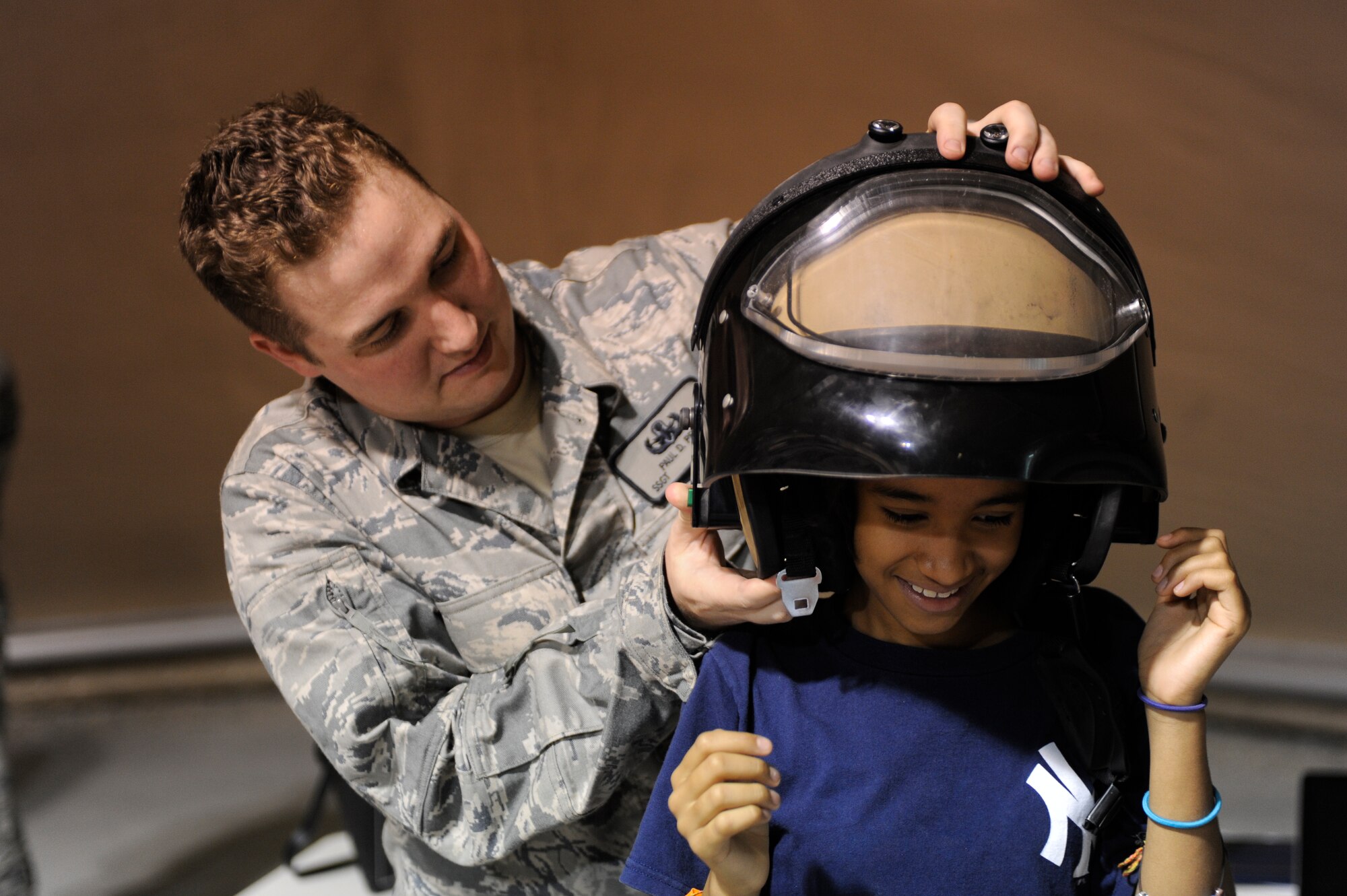 Staff Sgt. Paul Pest helps Alexandria Pacheco, 11, try on a bomb suit helmet during a U.S. Embassy Family Day tour of the Transit Center at Manas, Kyrgyzstan, Aug. 20. Pest is a 376th Expeditionary Civil Engineer Squadron explosive ordnance disposal technician, deployed here from Seymour Johnson Air Force Base, N.C. (U.S. Air Force photo/Tech. Sgt. Tammie Moore)