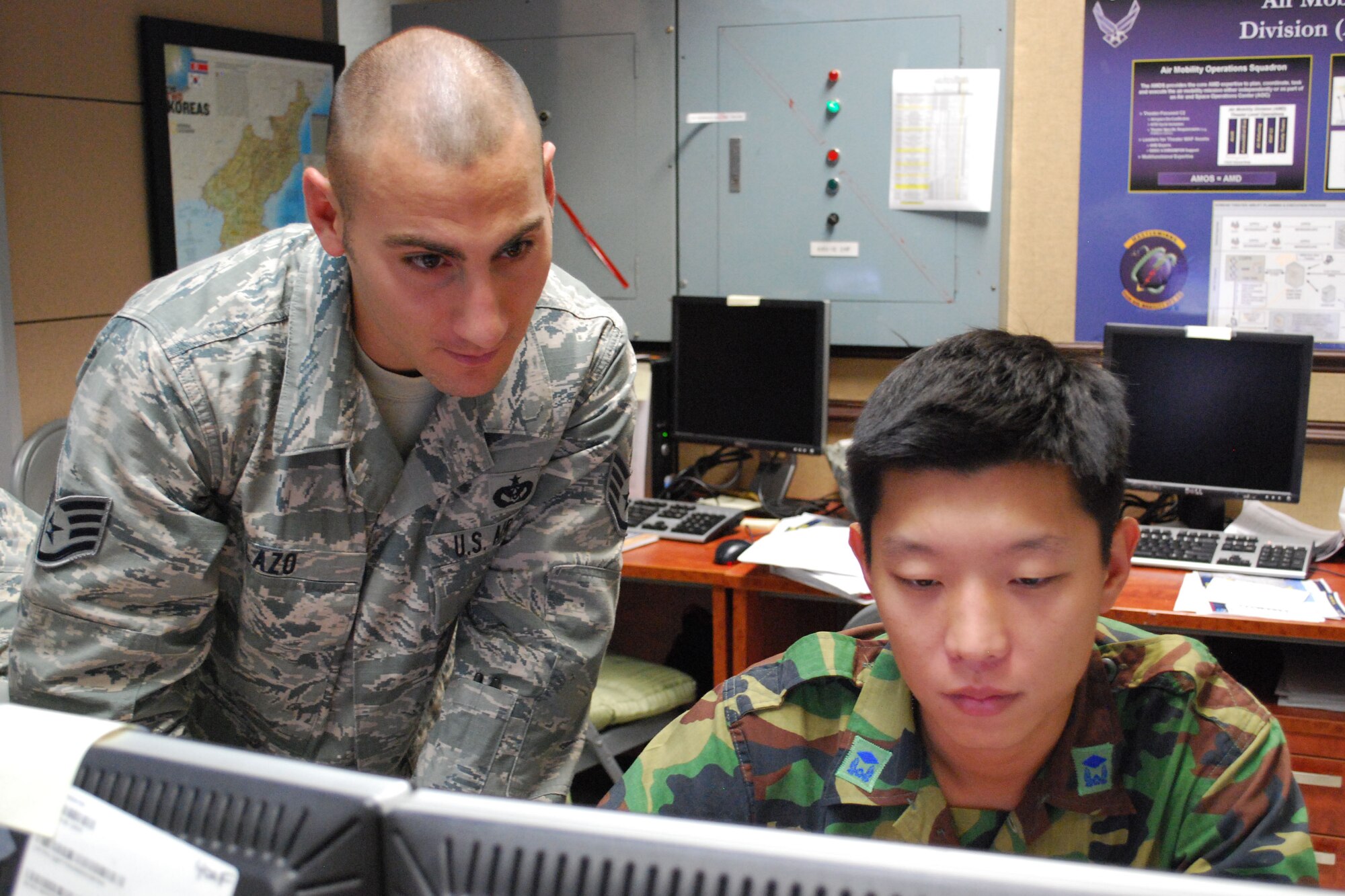 Staff Sgt. Daren Lazo, Reports and Analysis NCO, (left) and 2Lt. Hyunil Lee, Republic of Korea Combined Air Mobility Division interpreting officer, review presentation materials to ensure translation accuracy.  (U.S. Air Force photo/Capt. Paradon Silpasornprasit)