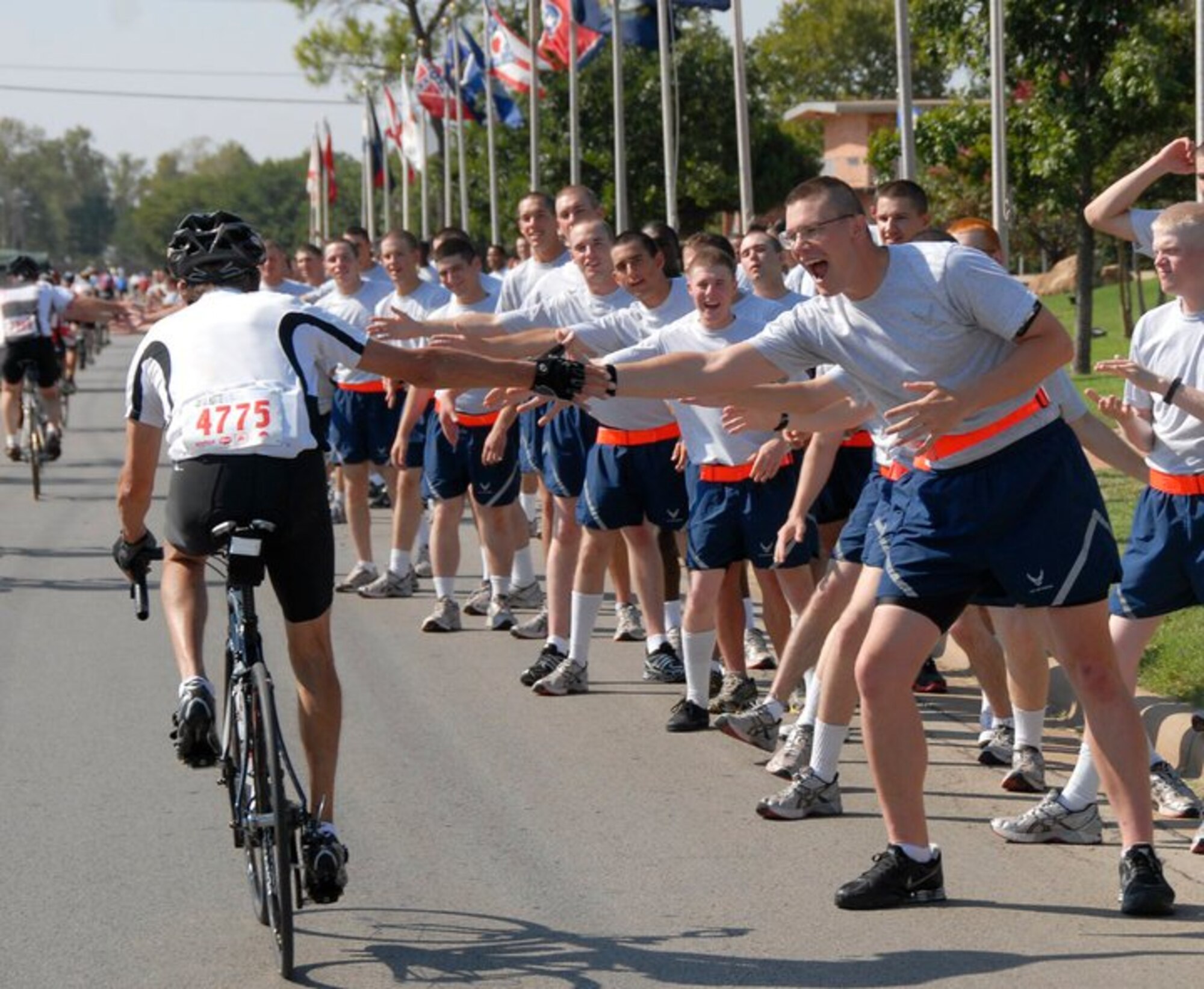 Riders in the Hotter n’ Hell Hundred bike race give high-fives as they ride through "Airman Alley" Aug. 28, 2010 at Sheppard Air Force Base, Texas. Some riders also stopped at the “Pits Stop” where Airmen volunteered to hold bicycles and serve refreshments and were able to visit with pilots as they rode through "Air Power Alley." The HHH will be celebrating it’s 30th anniversary Aug. 27 and has grown to more than 15,000 riders with record-breaking numbers of participants signing up each year. (U.S. Air Force courtesy photo)