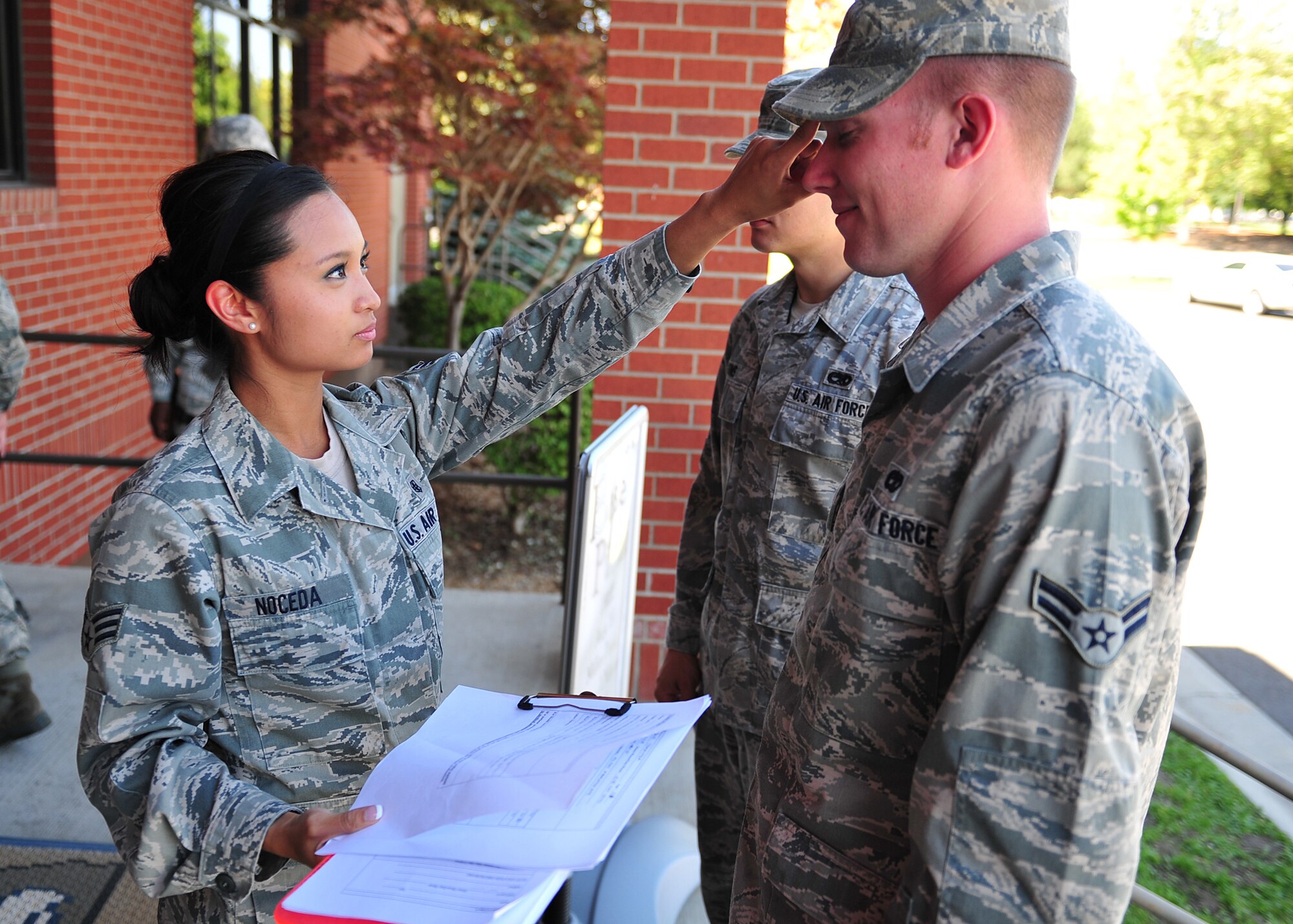 Senior Airman Pauline Noceda, 92nd Medical Support Squadron, checks the temperature of Airman 1st Class Devin Tatman, 92nd Aircraft Maintenance Squadron, and looks for signs and symptoms of the Pneumonic Plague during the exercise Aug. 17. Clinical teams prescribed medication and evaluated patients. Public health briefed those infected, mental health checked patients’ mental and emotional stability and pharmacy personnel dispensed medicine. (U.S. Air Force photo/Staff Sgt. Michael Means)