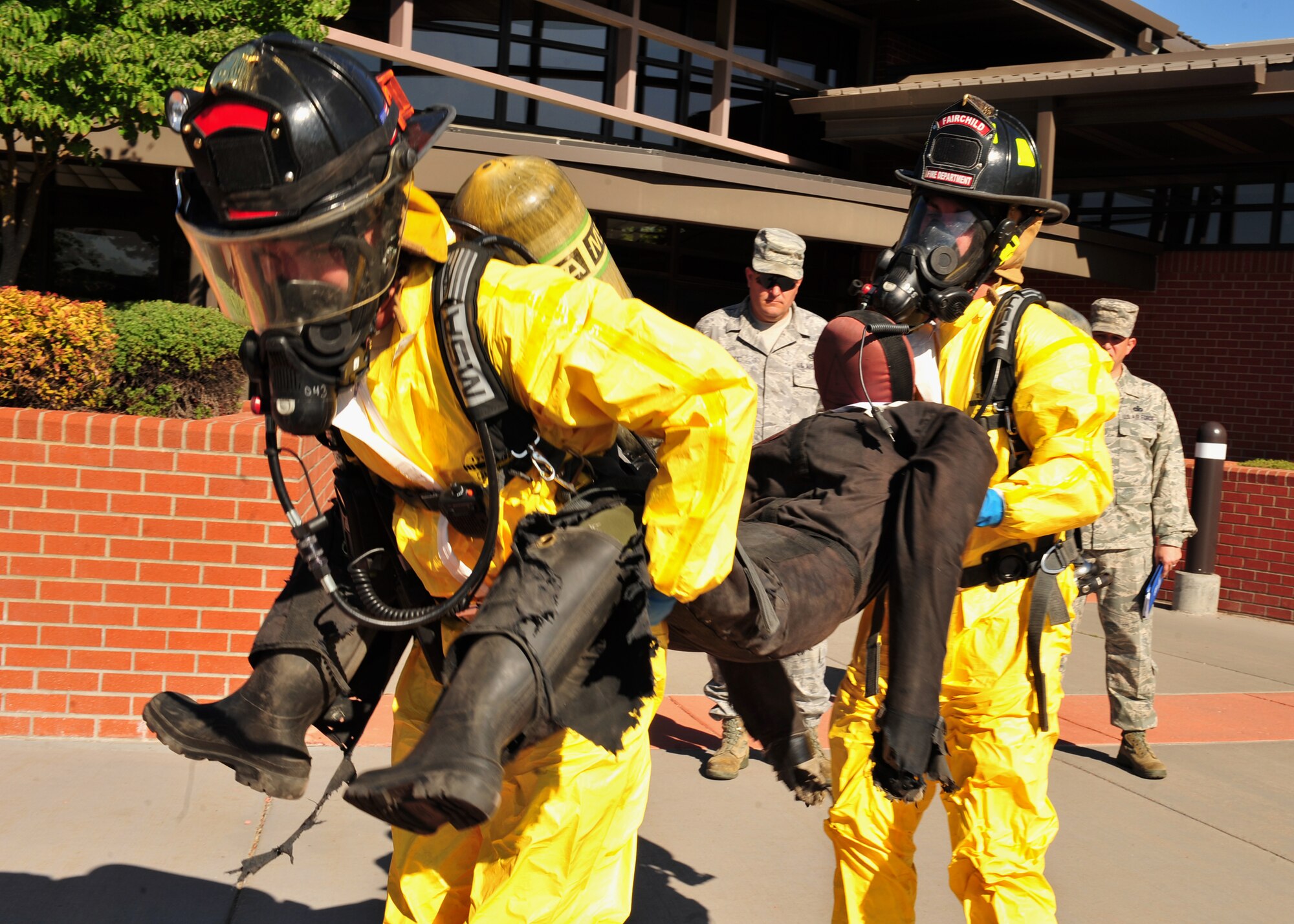 Members of the 92nd Civil Engineer Squadron fire department carry a victim to safety during the first-ever disease containment plan exercise at Fairchild Aug. 17. (U.S. Air Force photo/Staff Sgt. Michael Means)