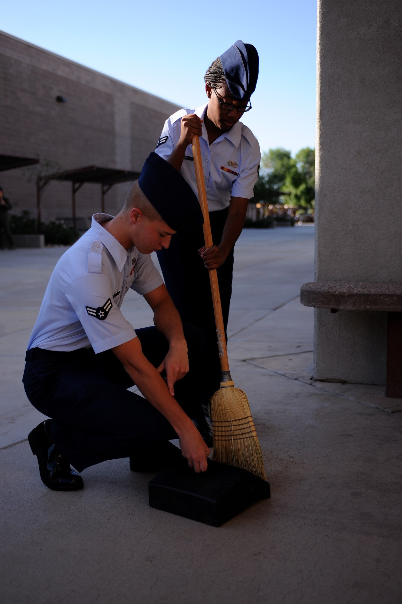 DAVIS-MONTHAN AIR FORCE BASE, Ariz. – Airman 1st Class Jaime Heathe, 355 Operational Weather Squadron, sweeps as Airman 1st Class Luke Ivazic, 355 Component Maintenance Squadron,  holds the dust pan here Aug 25. The center is designed to help first-term Airmen transition from technical school to a first duty station environment. (U.S. Air Force photo/Airman 1st  Class Christine Halan)