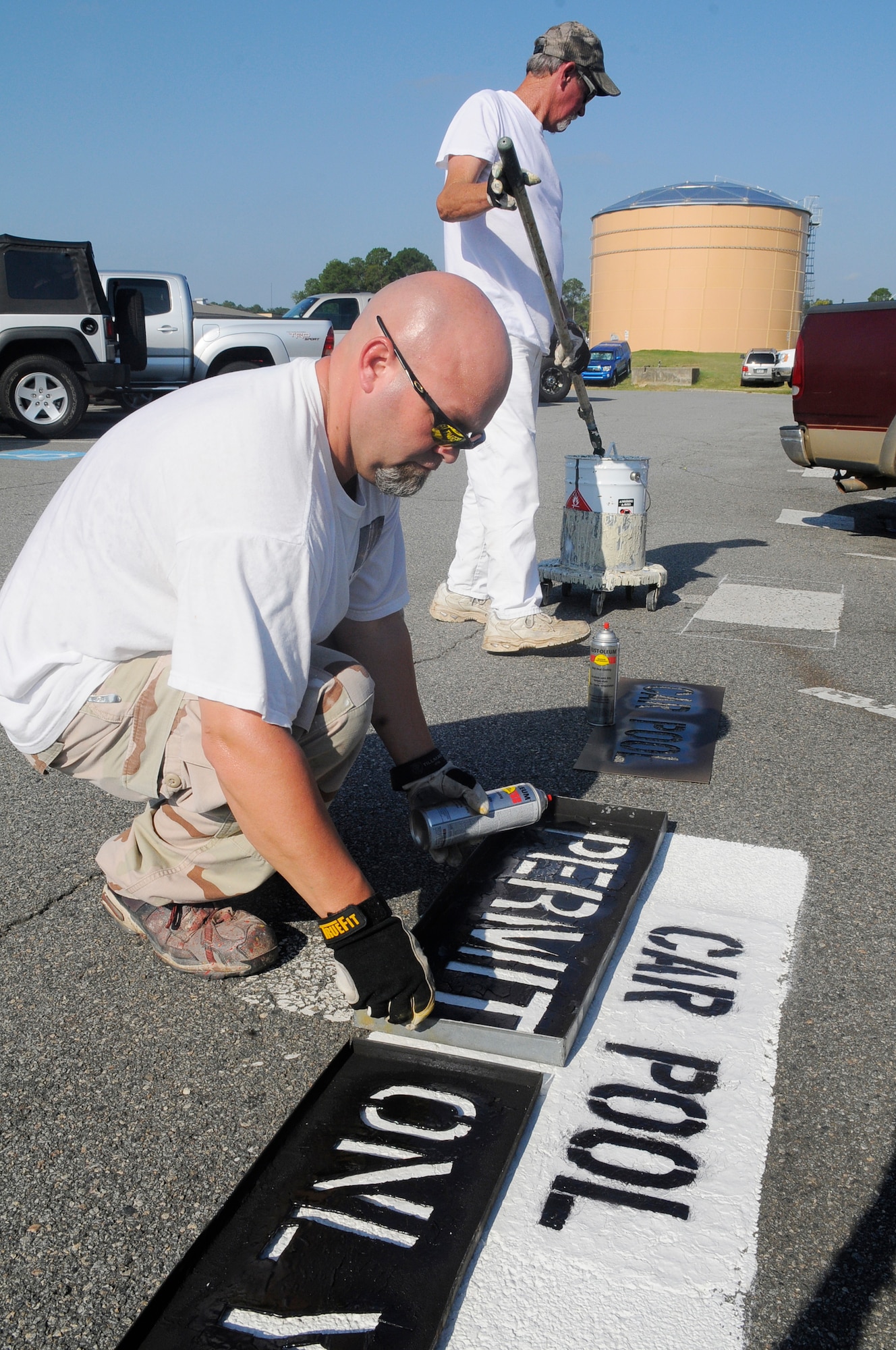 Eric Wheeless and Fred Howard, 78th CES painters, prepare new parking spaces for carpool permit parking in the parking lot near the overpass bridge. A total of 23 parking spaces in various areas have been initially reserved for the initiative. U. S. Air Force photo by Sue Sapp
