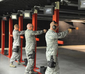 A muzzle flash can be seen as (right to left) Chief Master Sgt. George Skender, Air Force Recruiting Service Inspector General Office, Master Sgt. Brian Thornton, 902nd Contracting Squadron, and Master Sgt. Justin Carrington, Air Force Recruiting Service, fire for effect during small arms training at the Randolph Air Force Base firing range Aug. 15. (U.S. Air Force photo/Rich McFadden) (released)