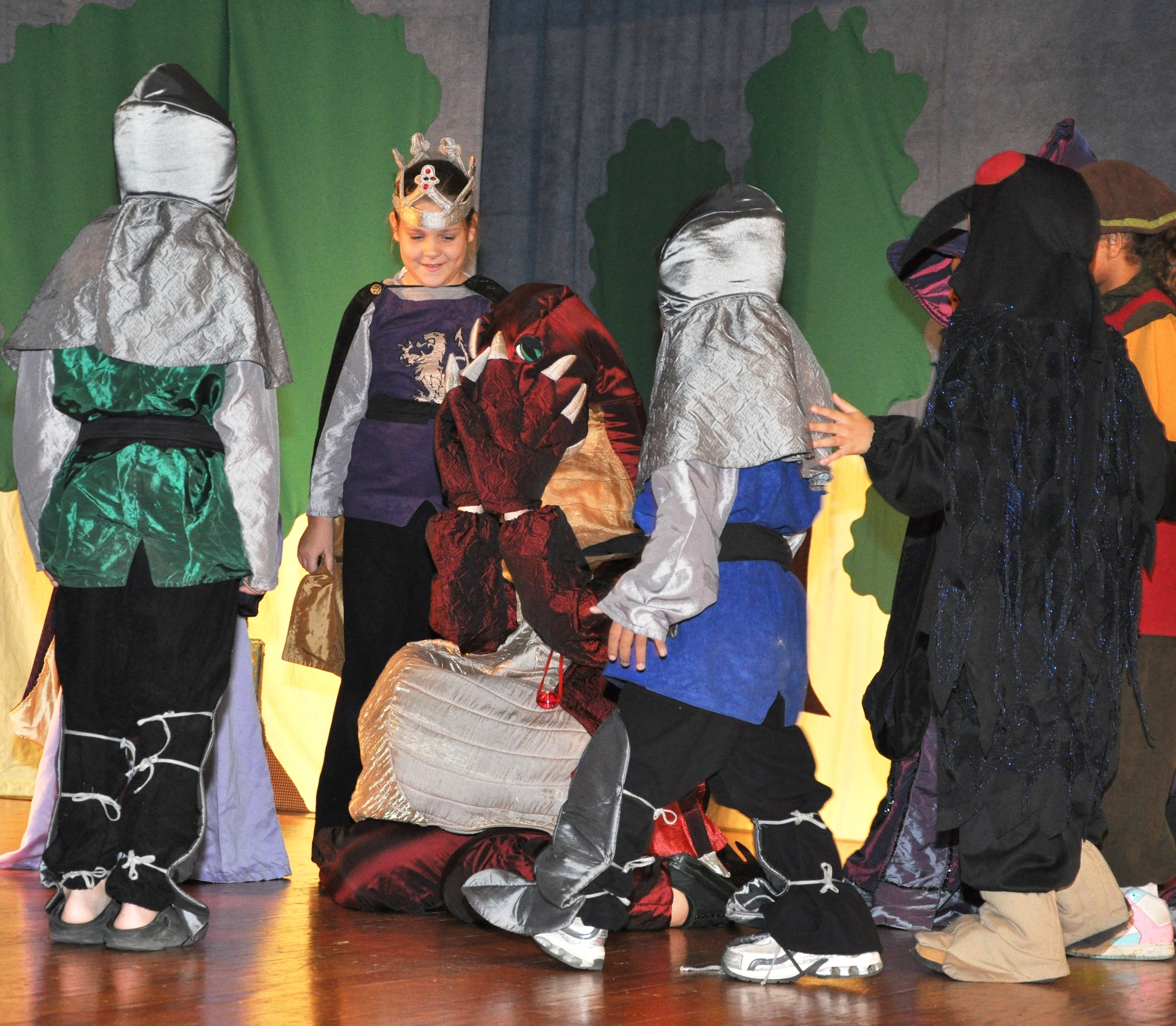 GOODFELLOW AIR FORCE BASE, Texas -- The Minis try to hep the intractable dragon with his tooth ache during the Missoula Children's Theatre production of King Arthur's Quest Aug. 20 at the base theater here.  The Missoula Children's Theatre travels to 1,300 communities in the United States and in 17 countries each year fostering development life skills in more than a million youths.  (U.S. Air Force photo/Connie Hempel)