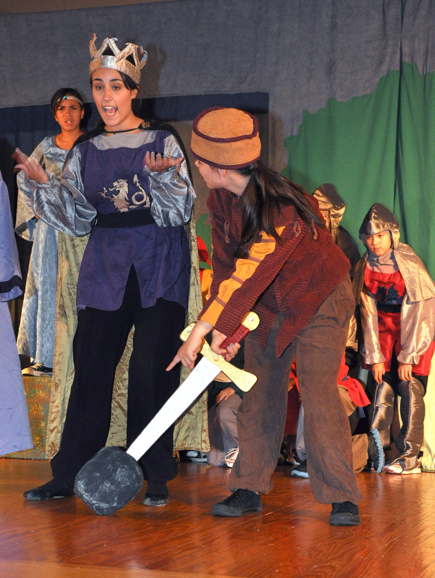 GOODFELLOW AIR FORCE BASE, Texas -- Keeper of the Keep, played by Loretta Underwood, tries to give King Arthur, played by Emily Hunnemeyer, his sword while it's still stuck in a rock during the Missoula Children's Theatre production of King Arthur's Quest Aug. 20 at the base theater here.  More than 50 youths were cast for this year's event. (U.S. Air Force photo/Connie Hempel)