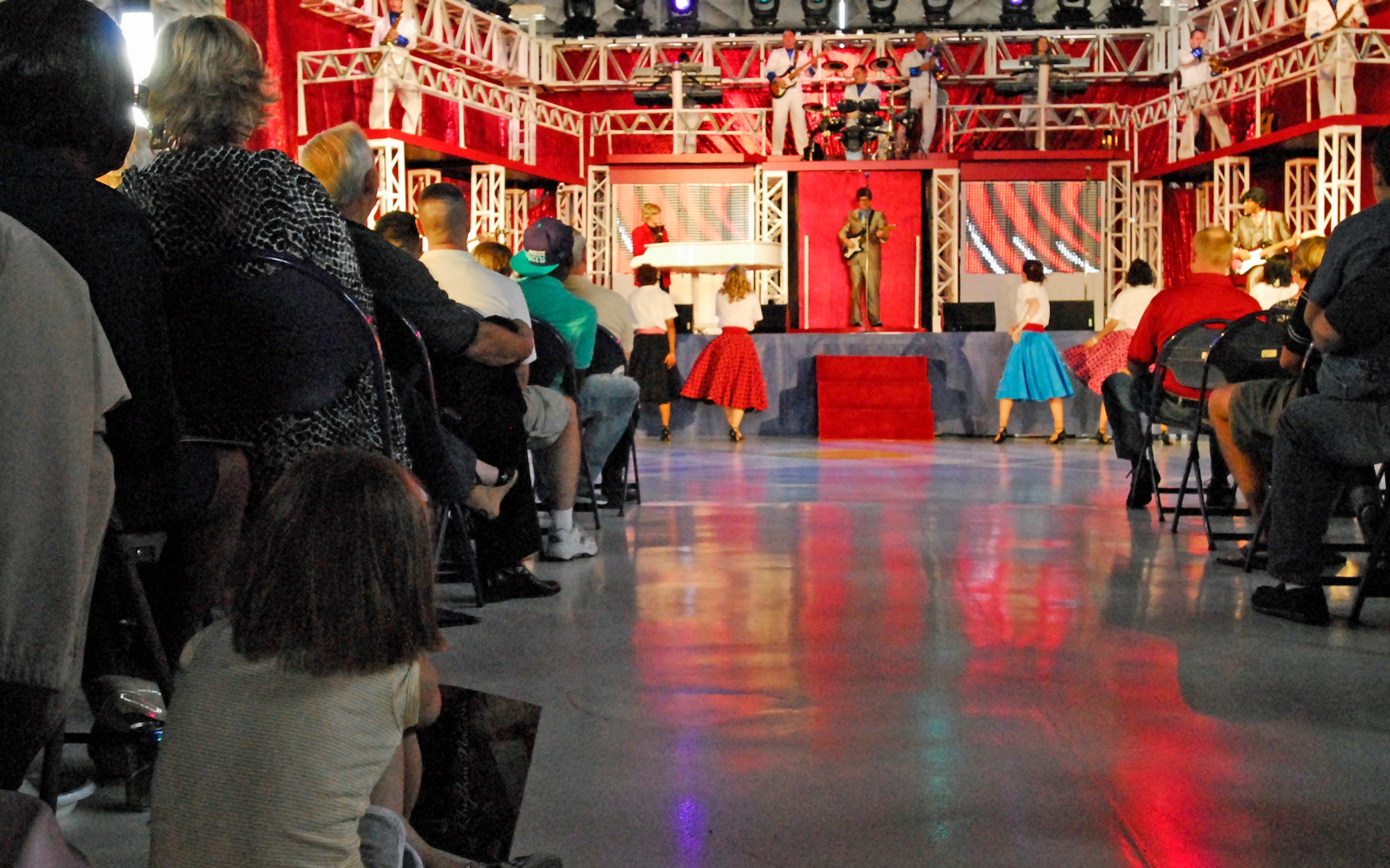 A young girl watches as the Air Force’s premier entertainment group, Tops in Blue, perform in Hangar 140 on Peterson Air Force Base, Aug. 21. This year’s TiB tour theme is "Rhythm Nation." (U.S. Air Force photo/Senior Airman Jessica Hines)