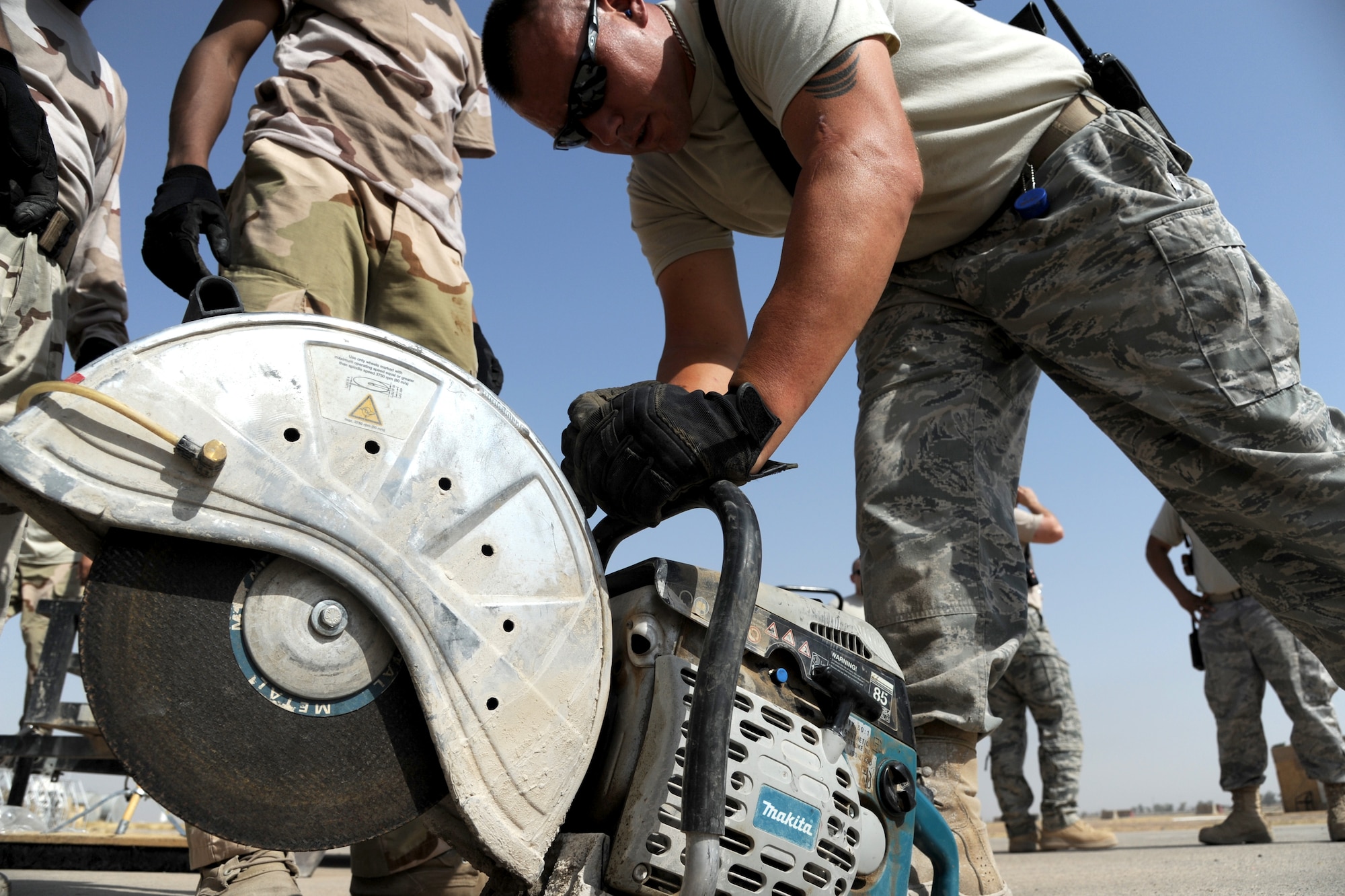 Staff Sgt. Kenneth Collins, 321st Expeditionary Operations Support Squadron, prepares to cut grooves into a defective patch of pavement on the flight line at Kirkuk Air Base.  The team responds with the Iraqis to teach them how to repair small discrepancies on the flight line by cutting grooves, breaking up pavement, and filling a man made hole with cement to help keep the runway smooth. (U.S. Air Force photo by Senior Airman Tristin English)