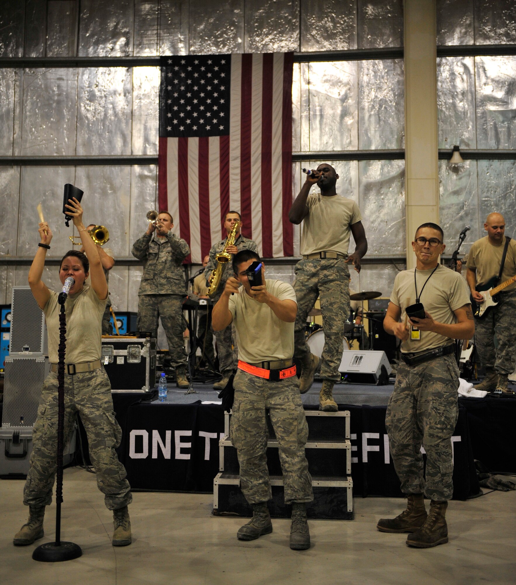 Sidewinder, the U.S. Air Forces Central Command band, gets the crowd involved during a set at the 380th Air Expeditionary Wing Aug. 21, 2011, as members of the audience come on stage to play the cowbell. This show took place at a hangar on the flightline at 1:30 a.m. for flightline personnel who work nights and were unable to attend any of the other shows. (U.S. Air Force photo/Tech. Sgt. Patrick Mitchell)
