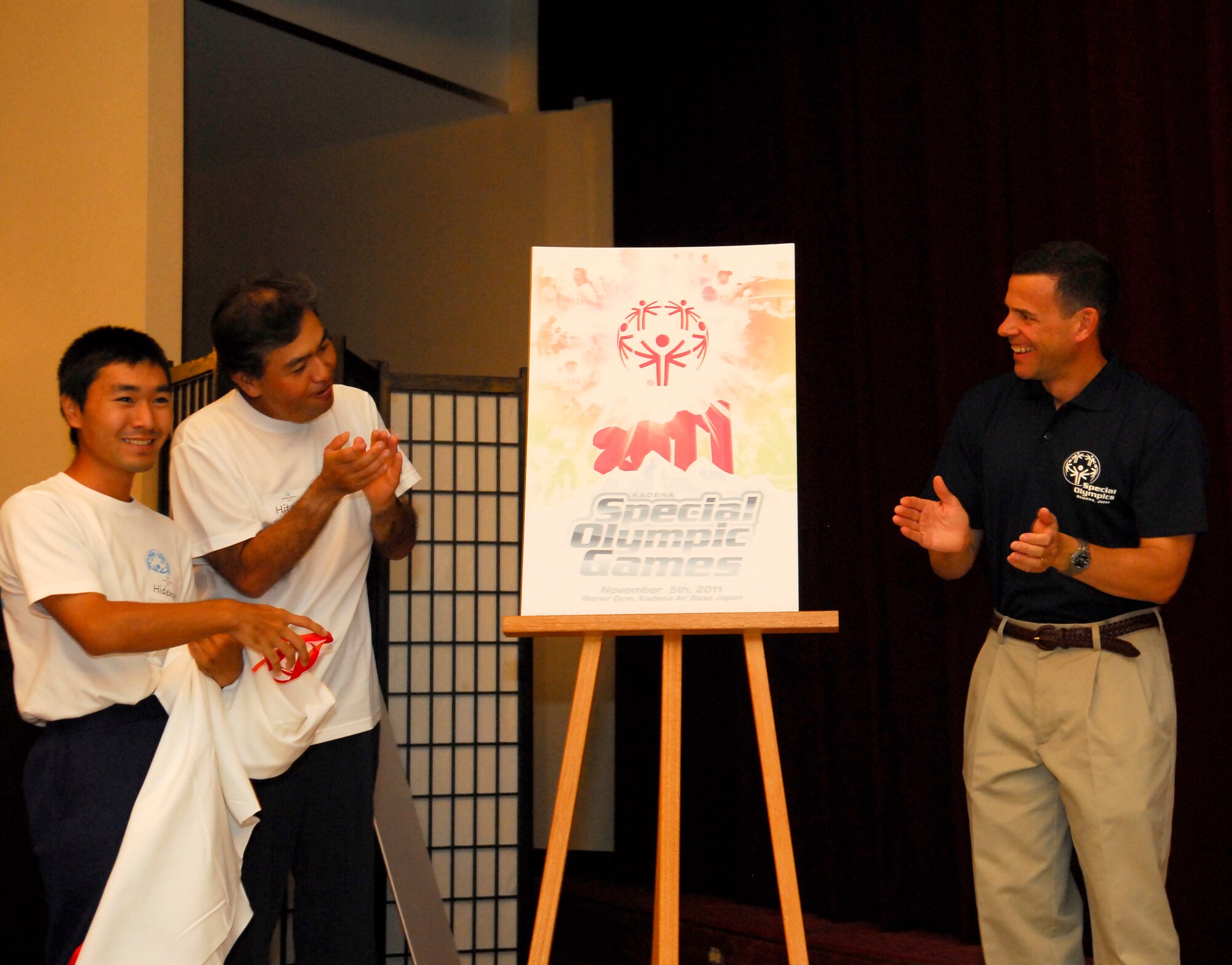 Eisa dancers from the Kuwonmoi organization help Brig. Gen. Matt Molloy, 18th Wing commander, reveal the 12th annual Kadena Special Olympics poster at the KSO Pep Rally at Kadena Air Base, Japan, Aug. 24. The Eisa dancers are students with the Kuwonmoi organization which holds workshops for locals with special needs. The dancers are also special-needs athletes. The KSO Pep Rally kicked off a series of events leading up to the 12th annual KSO one-day sporting and entertainment event with over 1,000 special-needs athletes and artists participating in a day of competition, music and special recognition. (U.S. Air Force photo/1st Lt. Natassia Cherne)