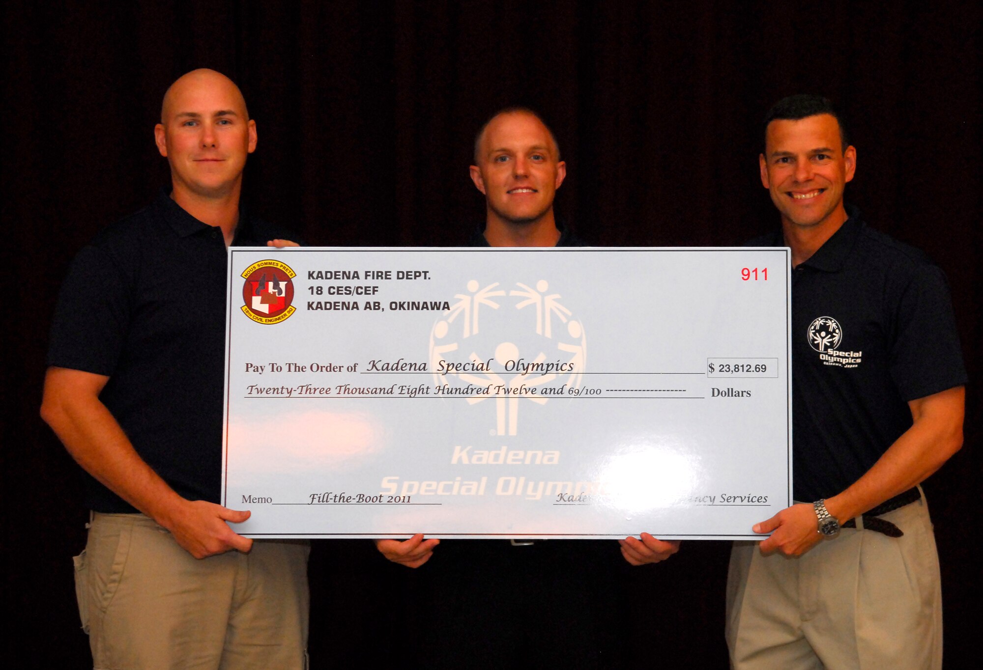 Tech. Sgt. Jeffrey Ruffenach and Staff Sgt. George Dowling, firefighters representing the 18th Civil Engineer Squadron, present Brig. Gen. Matt Molloy, 18th Wing commander, with a check for over $23,000 for the Kadena Special Olympics at Kadena Air Base, Japan, Aug. 24. The firefighters raised the most amount of funds ever this year from their annual "Fill the Boot" fundraiser for the 12th annual KSO. The event is a one-day sporting and entertainment event with over 1,000 special-needs athletes and artists participating in a day of competition, music and special recognition. (U.S. Air Force photo/1st Lt. Natassia Cherne)