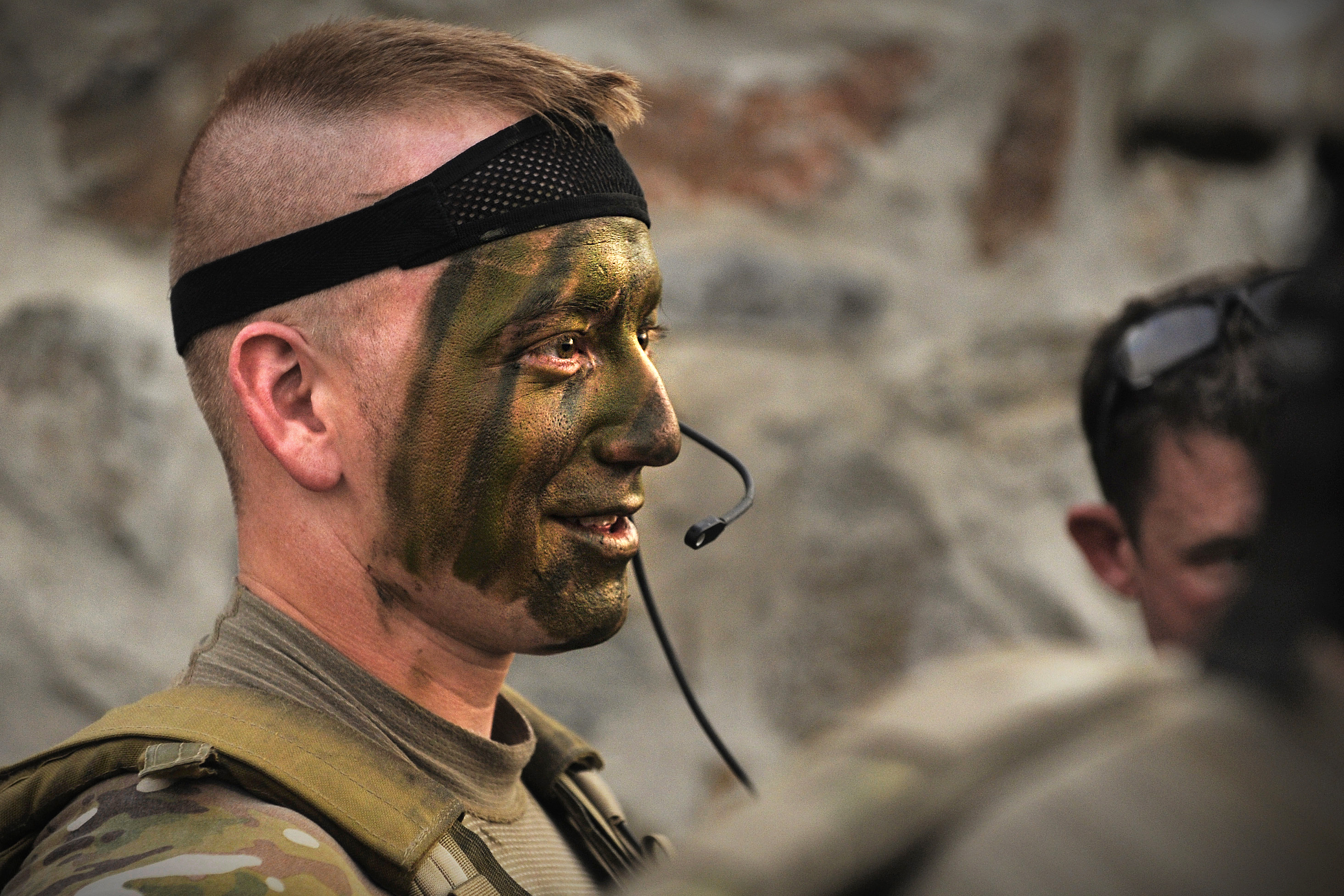 U.S. Army Spc. Dan White watches as fellow soldiers apply camouflage face  paint before an operation