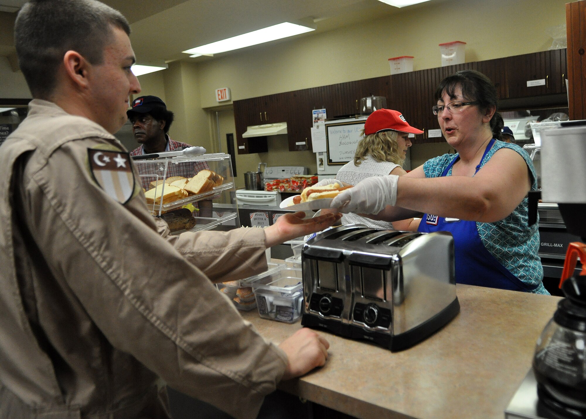 A USO volunteer hands a few hot dogs to Airman 1st Class Auston Witherrite, 8th Airlift Squadron loadmaster, before the squadron left for deployment August 25, 2011, at Joint Base Lewis-McChord, Wash. Airmen assigned to the 8th AS departed McChord Field August 26 for a 120-day deployment in support of the Operations New Dawn and Enduring Freedom.  (U.S. Air Force photo/Airman 1st Class Leah Young) 