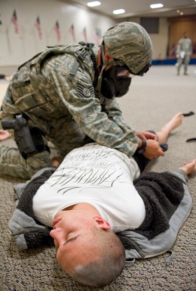 Tech. Sgt. William Townsend, 2nd Security Forces Squadron flight chief, searches a simulated casualty during a scenario at Hoban Hall on Barksdale Air Force Base, La., Aug. 25. Townsend wore a gas mask during the scenario due to the possibility of a chemical attack. The simulation was part of a major accident response exercise. (U.S. Air Force photo/Senior Airman Chad Warren) (RELEASED)