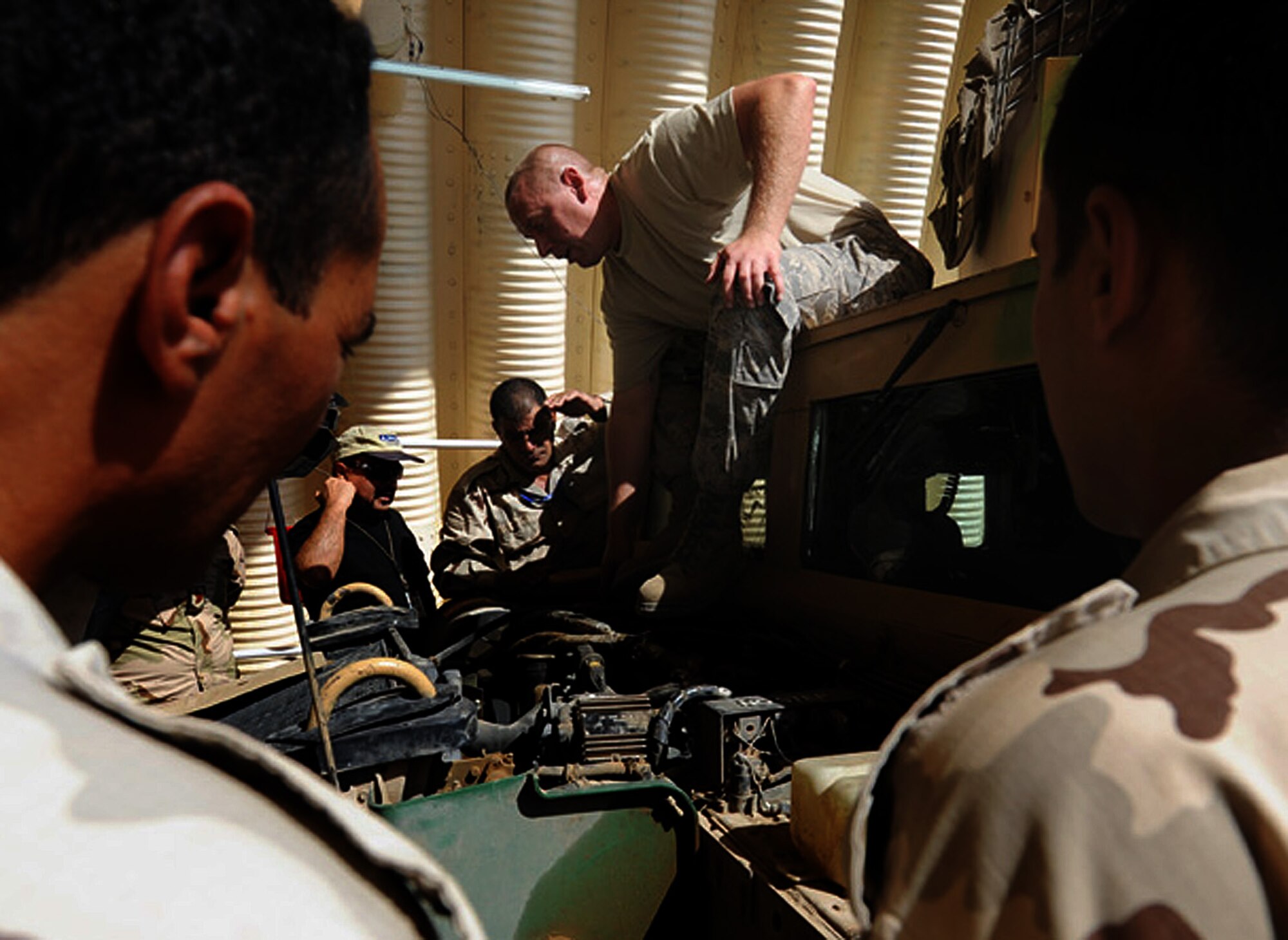 Tech. Sgt. David Townsend, shop foreman for vehicle maintenance, shows Iraqis how to perform basic vehicle maintenance on a Humvee at Kirkuk Air Base, Iraq.  (U.S. Air Force photo by Senior Airman Tristin English)