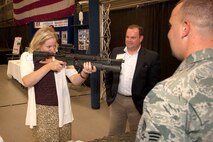 HANSCOM AIR FORCE BASE, Mass. - Tracy West, director of signature programs for the Red Sox Foundation and Mass. General Hospital Home Base program, takes aim during a visit to the 66th Security Forces Squadron display at the Electronic Systems Center Showcase at the Hanscom Aero Club Hangar Aug. 22.  Robert Davis, U.S. Army Reserve Home Base veteran outreach coordinator, and Senior Airman Stephen Bartlett, 66th SFS, look on. The showcase offered attendees a chance to learn about ESC’s mission through displays and demonstrations. (U.S. Air Force photo by Mark Wyatt)