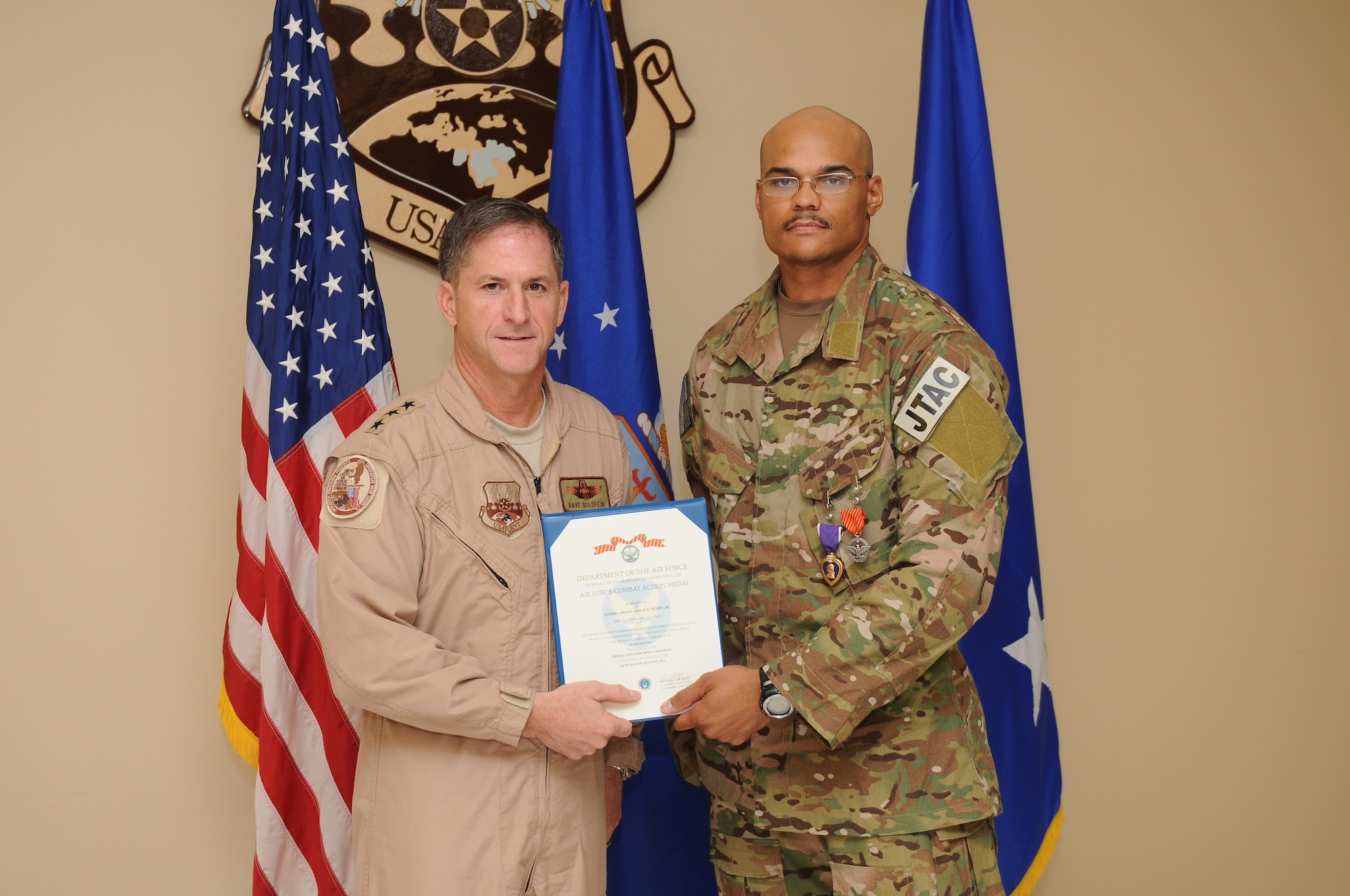 Senior Airman Jorge Henry, a joint terminal attack controller deployed to the 817th Expeditionary Air Support Operations Squadron, is presented an Air Force Combat Action Medal by Lieutenant General David Goldfein, commander of U.S. Air Forces Central Command, for actions taken during a nine-hour firefight in Afghanistan August 12, 2011. Henry, deployed from the 25th Air Support Operations Squadron, Schoefield Barracks, Hawaii, also sustained a gunshot wound to the hand early in the battle and continued to call in close air support throughout the firefight. He received the Purple Heart and the AFCAM August 25, 2011, while recuperating in Southwest Asia.(U.S. Air Force photo by Master Sergeant Gary J. Rihn)