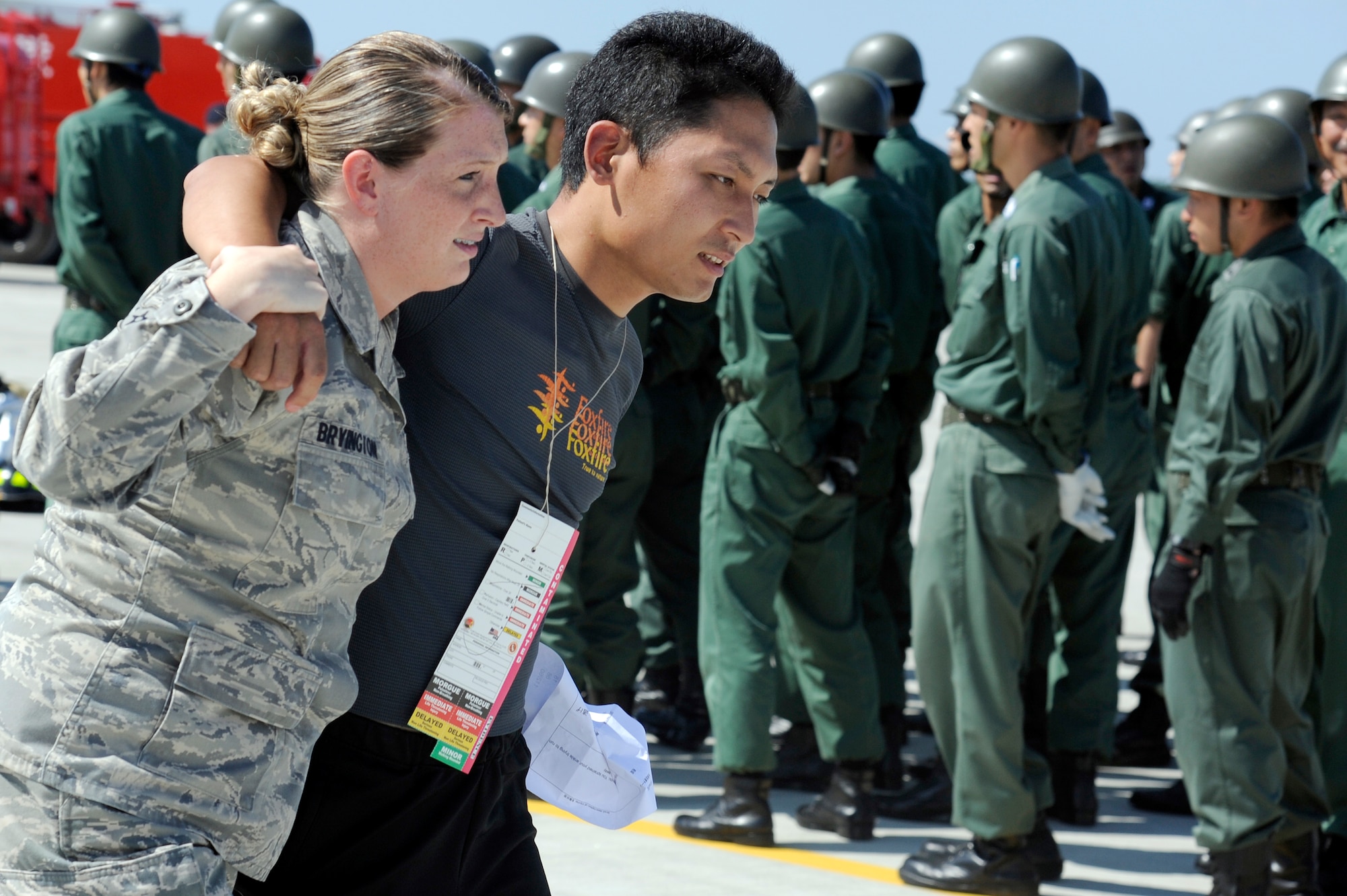 MISAWA AIR BASE, Japan -- Airman 1st Class Lacy Bryington, left, 35th Medical Group, escorts an injured role player away from a simulated crash scene during a major accident response exercise here Aug. 26. The MARE prepared emergency responders for the possibility of a real world accident during the upcoming Misawa Air Fest. (U.S. Air Force photo/Tech. Sgt. Marie Brown)