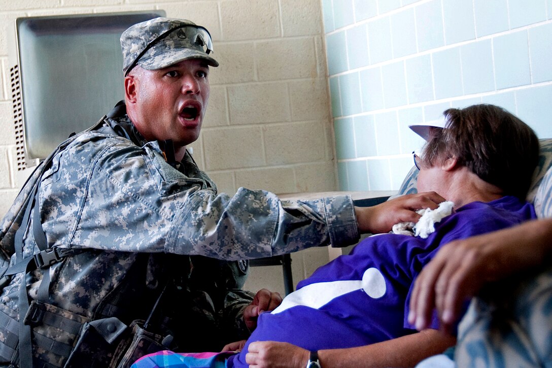 Army Staff Sgt. Cruz Munoz yells for assistance while helping a mock victim during Vibrant Response 12.1 at the Muscatatuck Urban Training Center in Butlerville, Ind., Aug. 21, 2011. Munoz is assigned to the 546th Military Police Company.