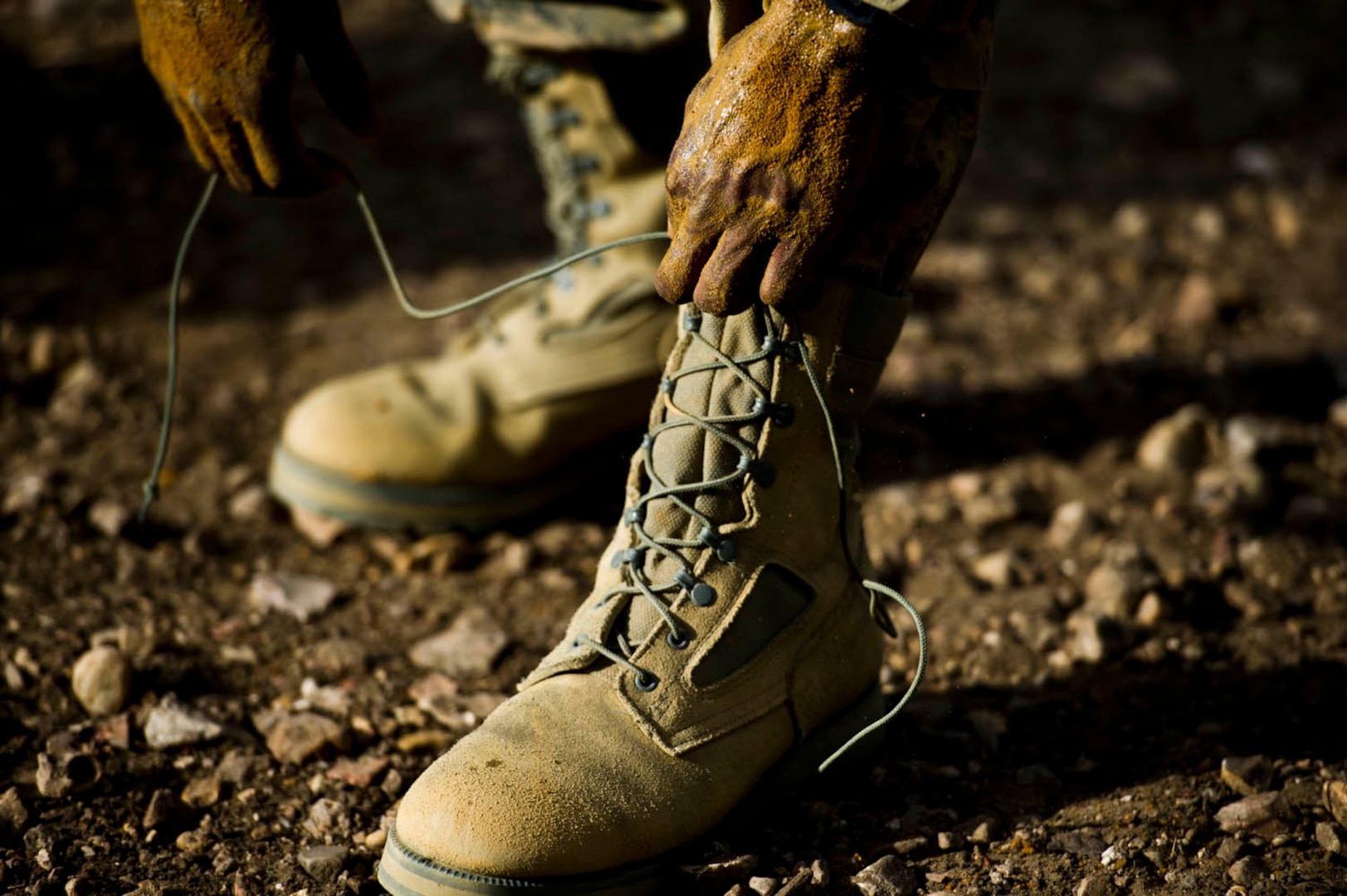 An Air Force basic military trainee reties his boots after completing the uphill low-crawl obstacle, part of the Creating Leaders, Airmen and Warriors (CLAW) course, July 27 at Lackland Air Force Base.  CLAW is a three-hour mission-oriented exercise designed to test teamwork, leadership skills and the ability to perform under pressure. (U.S. Air Force photo/Senior Airman Marleah Miller)