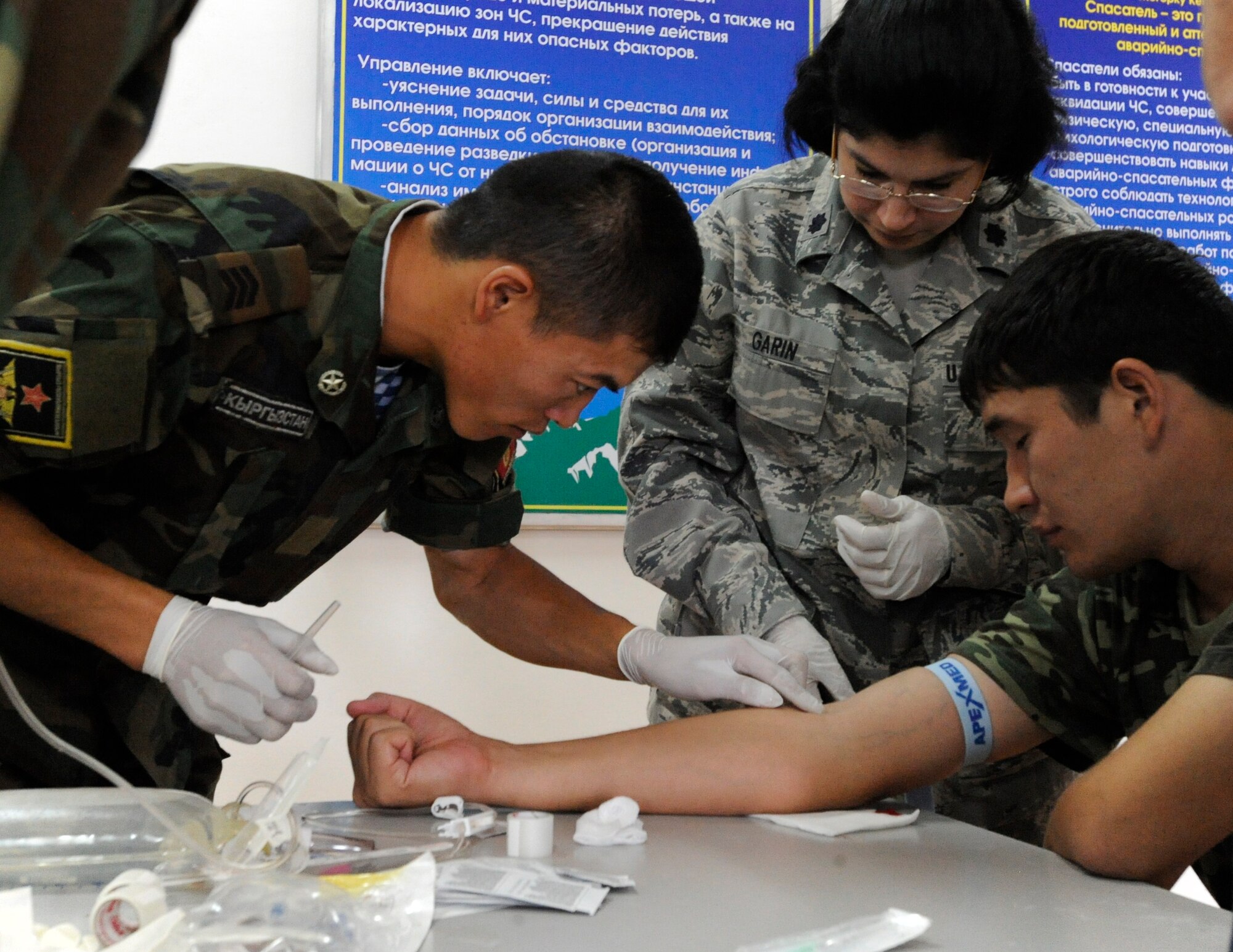 Lt. Col. (Dr.) Cecilia Garin observes as a Kyrgyz Republic soldier prepares to start an IV during a medical information exchange at the Kyrgyz Ministry of Emergency Services Aug. 25. The information exchange was lea by the Montana Army and Air National Guard. Garin is the 376th Expeditionary Medical Group dental services chief. She is deployed here from Joint Base McGuire-Dix-Lakehurst, N.J. (U.S. Air Force photo/Tech. Sgt. Tammie Moore) 
