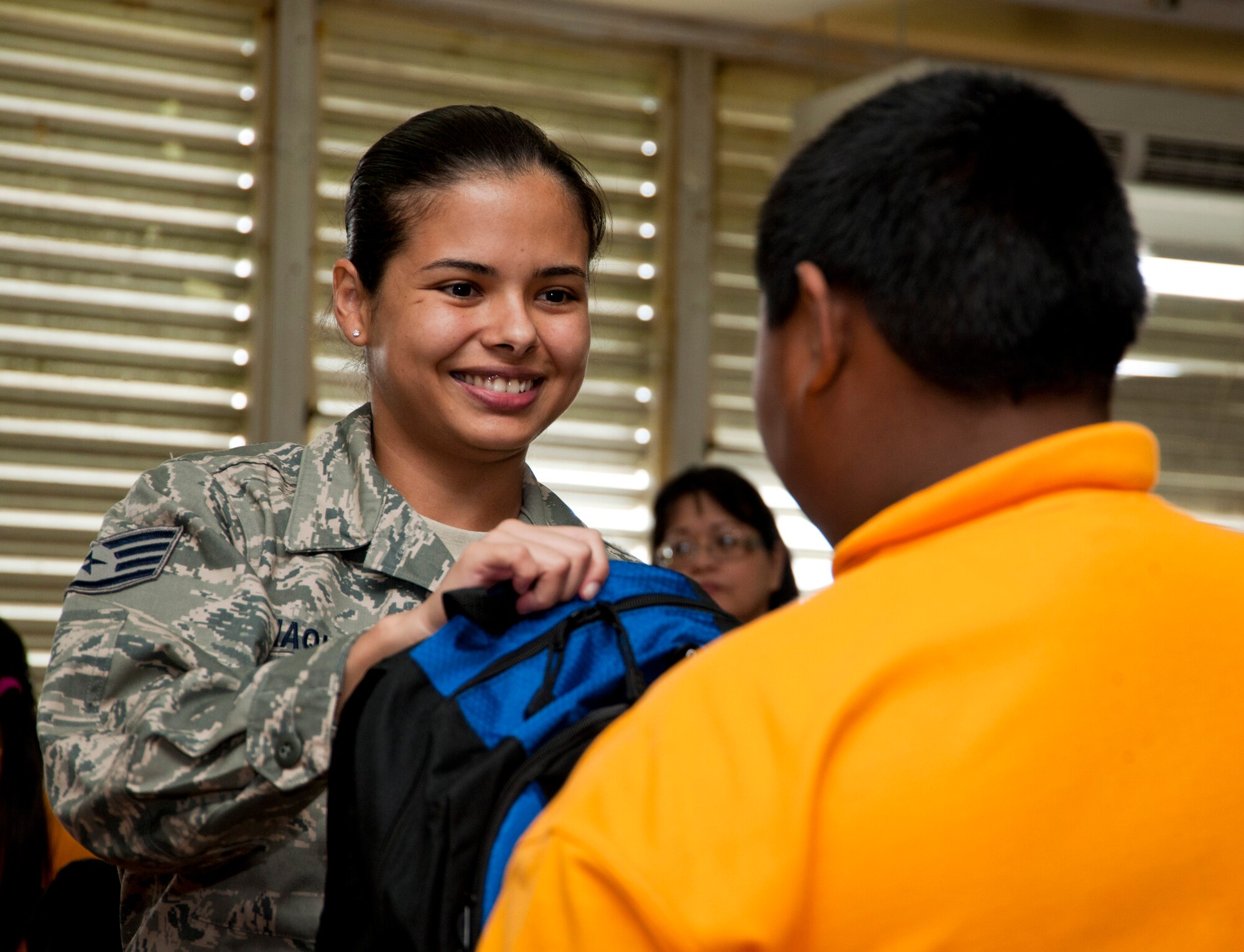 TALOFOFO, Guam— U.S. Staff Sgt. Sophia Idiaquez, 9th Operations Group Detachment 3 maintenance scheduling and planning, gives a backpack to a child from  the Talofofo Elementary School Aug. 25. The 9th OG adopted the Talofofo village and works closely with the local community throughout the year. (U.S. Air Force photo by Senior Airman Benjamin Wiseman/Released)