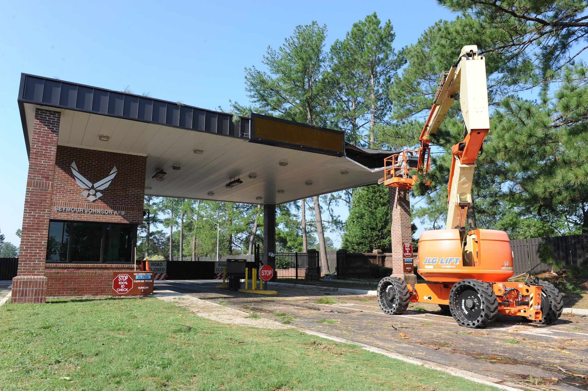 4th Civil Engineer Squadron work crews remove debris and loose trim from the Berkeley gate guard shack at Seymour Johnson Air Force Base, N.C., Aug. 28.  A falling tree impacted the roof, forcing officials to close the gate until the tree could be removed.  The Oak Forest gate handled the overflow until the debris could be cleared. 4th CES work crews were on site before dawn to begin cleanup that is expected to take several hours.  (U.S. Air Force photo by 1st Lt. Matt Schroff/Released)