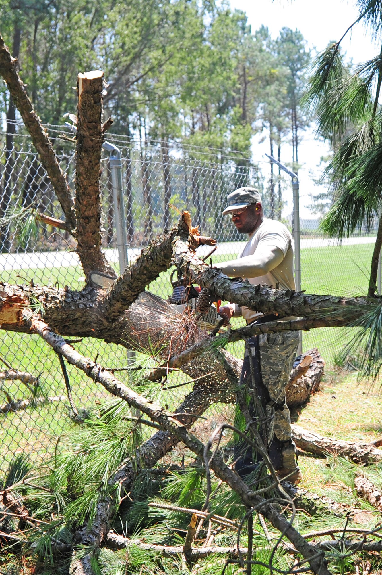 Staff Sgt. Emanuel Shiver uses a chainsaw to trim a tree limb down to a manageable size for removal by a front-end loader as part of the cleanup efforts from Hurricane Irene on Seymour Johnson Air Force Base, N.C., Aug. 28, 2011. Airmen from the 4th Civil Engineer Squadron began working around the clock shortly after winds died down Saturday afternoon to restore power and remove more than 40 downed trees. Shiver, 4th CES heavy equipment operator, is a native of Columbia, S.C. (U.S. Air Force photo by Senior Airman Rae Perry/Released)