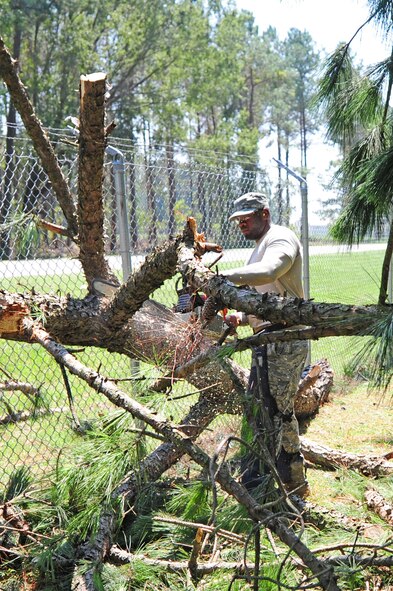 U.S. Air Force Staff Sgt. Emanuel Shiver uses a chainsaw to trim a tree limb down to a manageable size for removal by a front-end loader as part of the cleanup efforts from Hurricane Irene on Seymour Johnson Air Force Base, N.C., Aug. 28, 2011. Airmen from the 4th Civil Engineer Squadron began working around the clock shortly after winds died down Saturday afternoon to restore power and remove more than 40 downed trees. Shiver, 4th CES heavy equipment operator, is a native of Columbia, S.C. (U.S. Air Force photo by Senior Airman Rae Perry)