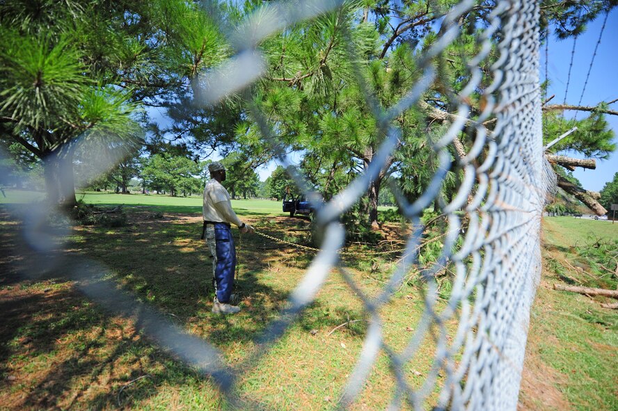 U.S. Air Force Staff Sgt. Emanuel Shiver prepares to pull a downed tree limb off the perimeter fence near the Oak Forest gate at Seymour Johnson Air Force Base, N.C., Aug. 28, 2011. After completing an assessment of damages, members of the 4th Civil Engineer Squadron work to restore power and remove trees that pose a security problem to the base. Shiver, 4th CES heavy equipment operator, is a native of Columbia, S.C. (U.S. Air Force photo by Senior Airman Rae Perry)