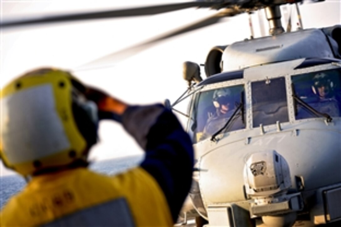 U.S. Navy Seaman Emmanuel Dixon signals a SH-60B Sea Hawk helicopter for landing during flight operations aboard the guided-missile cruiser USS Vicksburg  in the Atlantic Ocean, Aug. 27, 2011. Vicksburg was preparing to respond to damages caused by Hurricane Irene if requested. Dixon is a boatswain's mate and the helicopter is attached to Helicopter Anti-submarine Squadron Light 42.