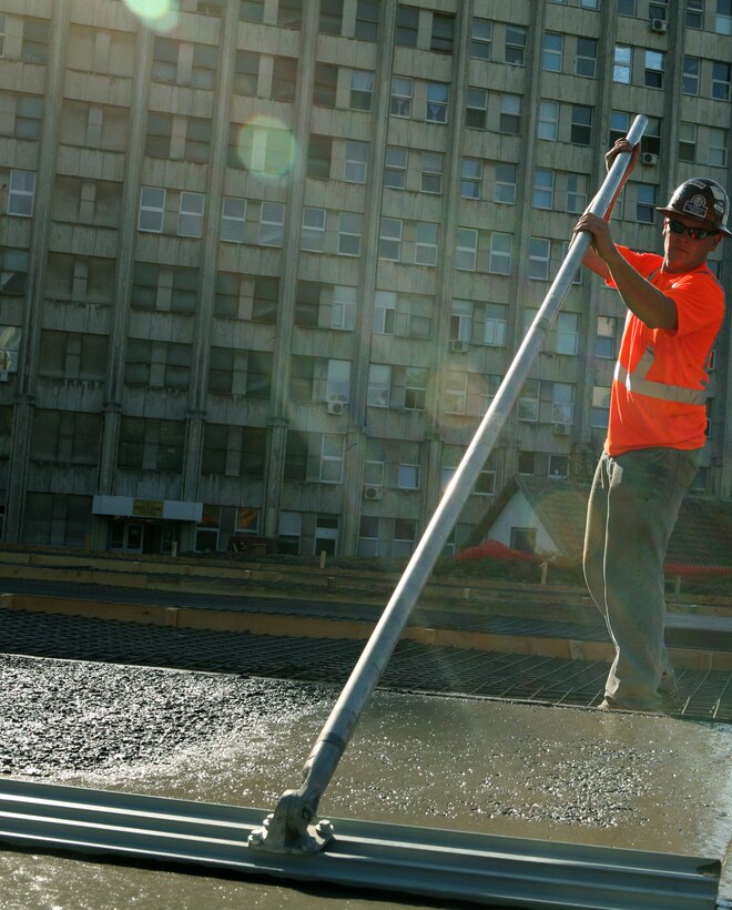 After the freshly-poured concrete is spread, Sgt. Matthew A. Houle , Wakefield, Mass., native and chief for the combat engineers, Black Sea Rotational Force 11, uses a “bull float” to put a smooth finish on what will be a new helipad for Constanta County Hospital. Combat engineers with Black Sea Rotational Force 11 contracted with Romanian excavation specialist to then buildt a helipad for Constanta County Hospital that will alleviate flight time for patients to the emergency room and will allow helicopter evacuation of critically-wounded patients to the trauma center at the hospital -- the only one within approximately 260 kilometers -- and potentially save lives. help to save more lives by getting casualties prompt and rapid medical care. The landing pad was part of the engineer’s last community relations project for the country before they are slated to depart back to the states this month.  ::r::::n::