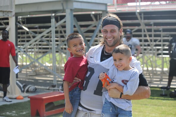 Scott Fambrough, Valdosta State University football team tight end, holds up two boys who attended a scrimmage in appreciation of Moody Air Force Base and military members, Aug. 26, 2011. During the practice, families were allowed to walk on the field and interact with players. (U.S. Air Force photo by Airman 1st Class Paul Francis/Released)