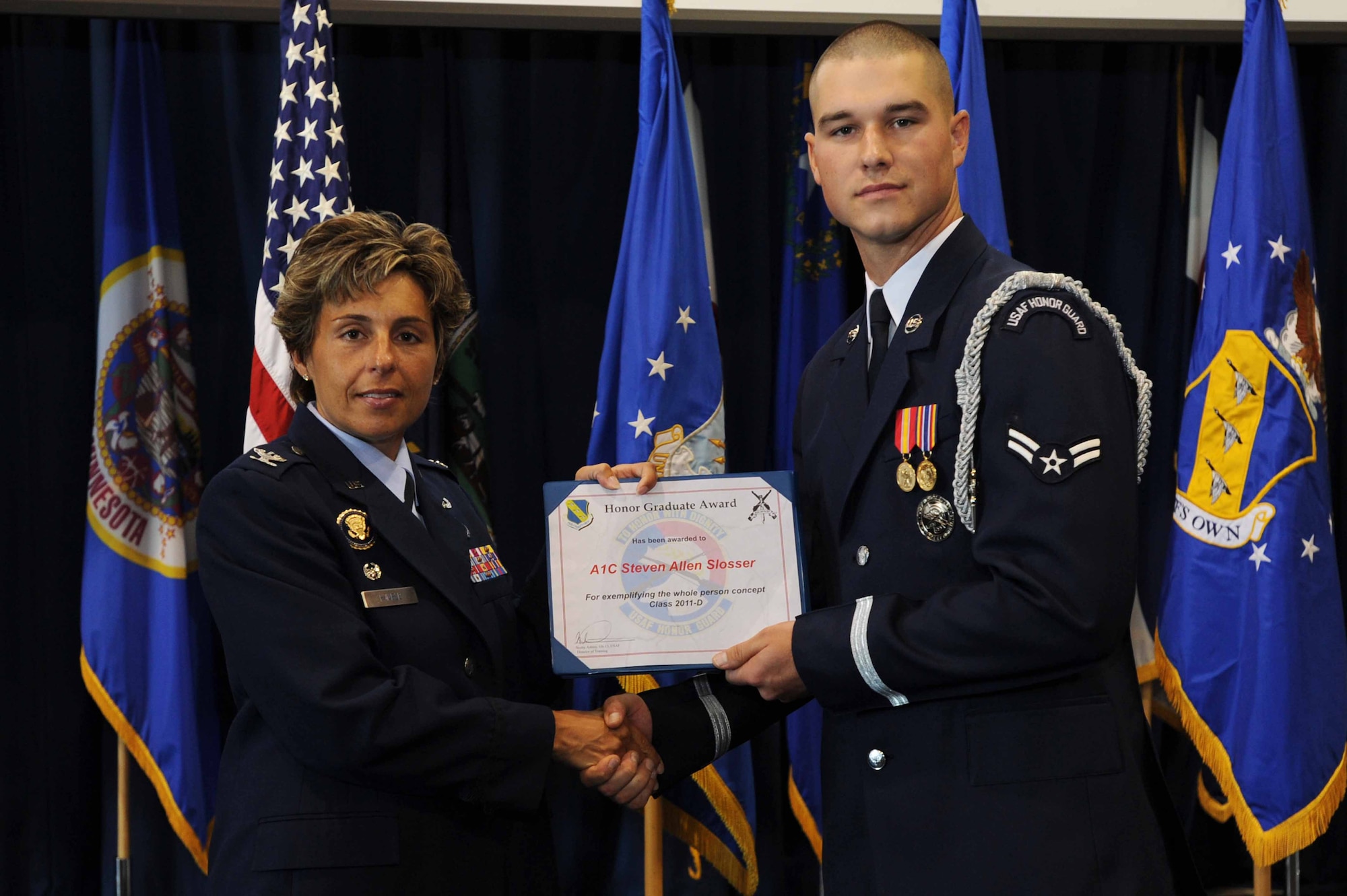 Airman 1st Class Steven A. Slosser, U.S. Air Force Honor Guard ceremonial guardsman, receives the Honor Graduate Award from Col. Gina C. Humble, 11th Operations Group commander, Aug. 26 on Joint Base Anacostia-Bolling, Washington D.C. The award is awarded to the top trainee who attains the highest score in the class during the USAF Honor Guard's eight week technical training school. (U.S. Air Force photo by Staff Sgt. Christopher Ruano)