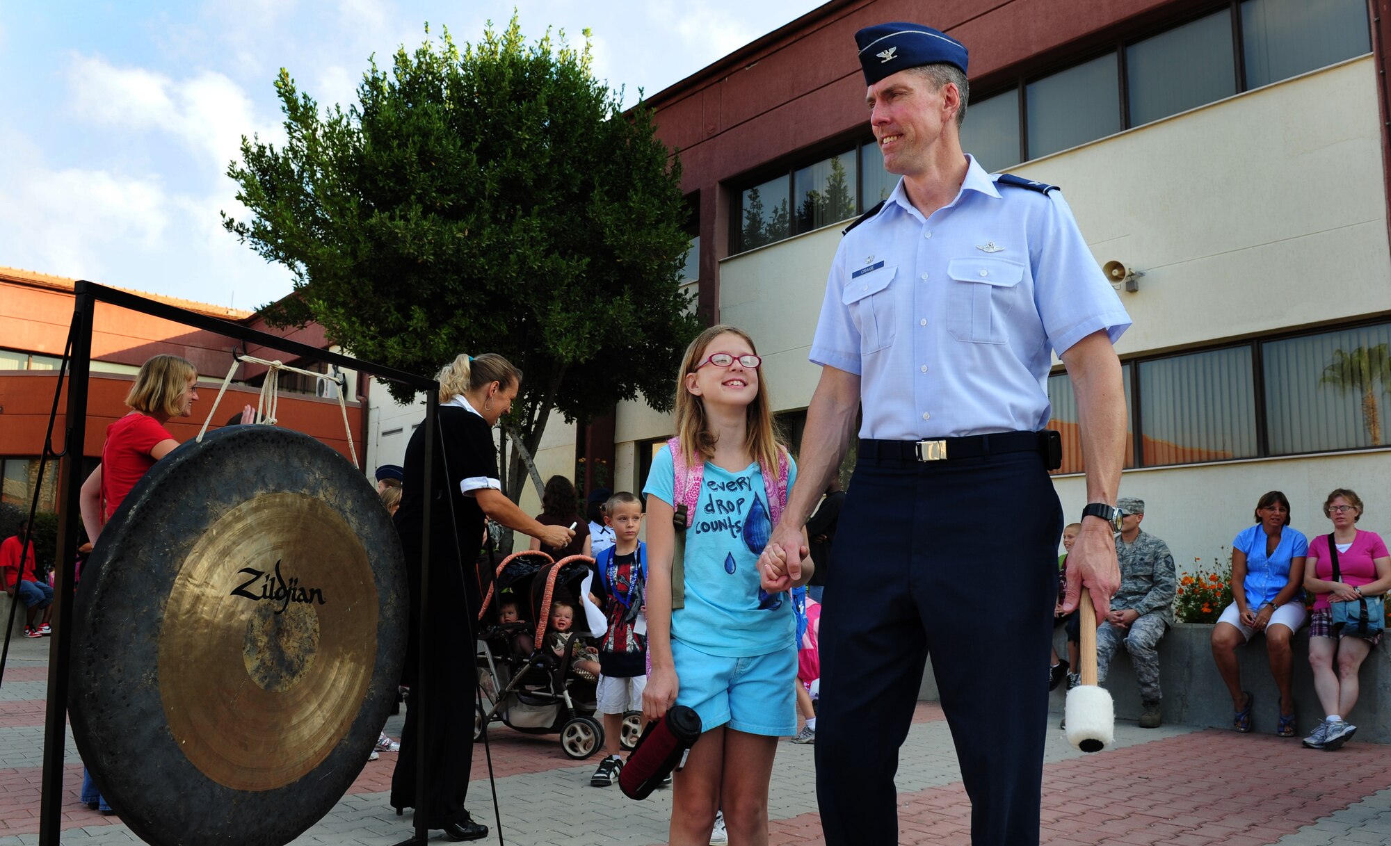 Col. Christopher Craige, 39th Air Base Wing commander, stands with his daughter before ringing a gong to signify the start of the school year Aug. 29, 2011, at Incirlik Air Base, Turkey. All grades began school today except kindergarten, which will begin the day after Labor Day. (U.S. Air Force photo by Senior Airman Anthony Sanchelli/Released)
