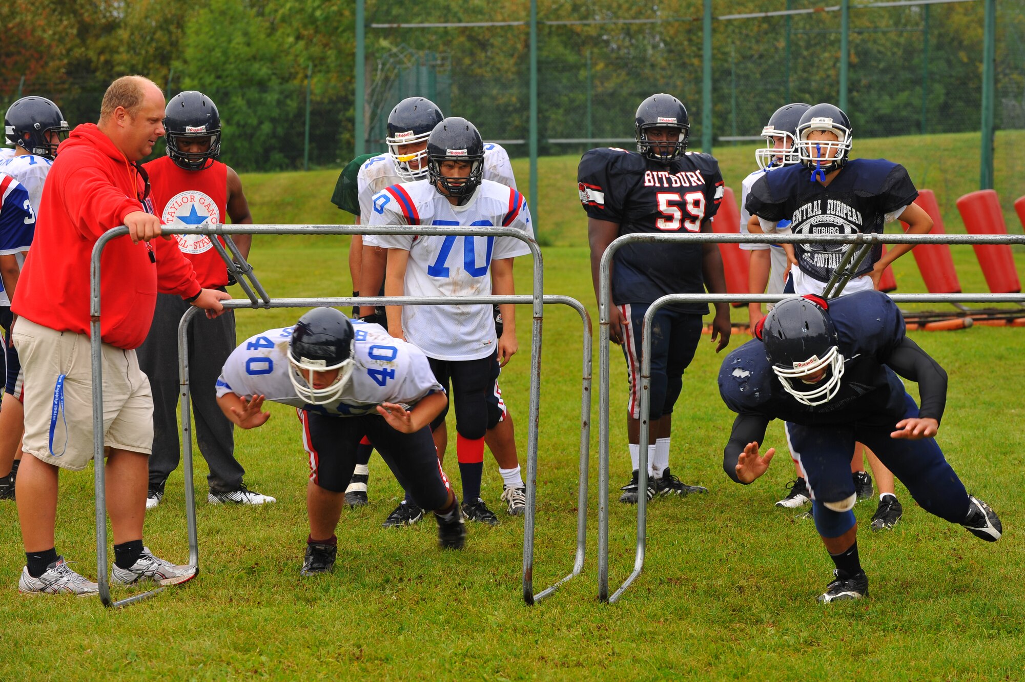 BITBURG ANNEX, Germany – Bitburg High School football players practice using a low stance for blocking during football practice here Aug. 24. The football team practices five days each week. Practices normally consist of a warm-up, cardio, strengthening exercises, hitting drills, blocking drills and running drills. The season tentatively kicks off with an away game against Heidleberg on Sept. 3. (U.S Air Force photo/Airman 1st Class Dillon Davis)