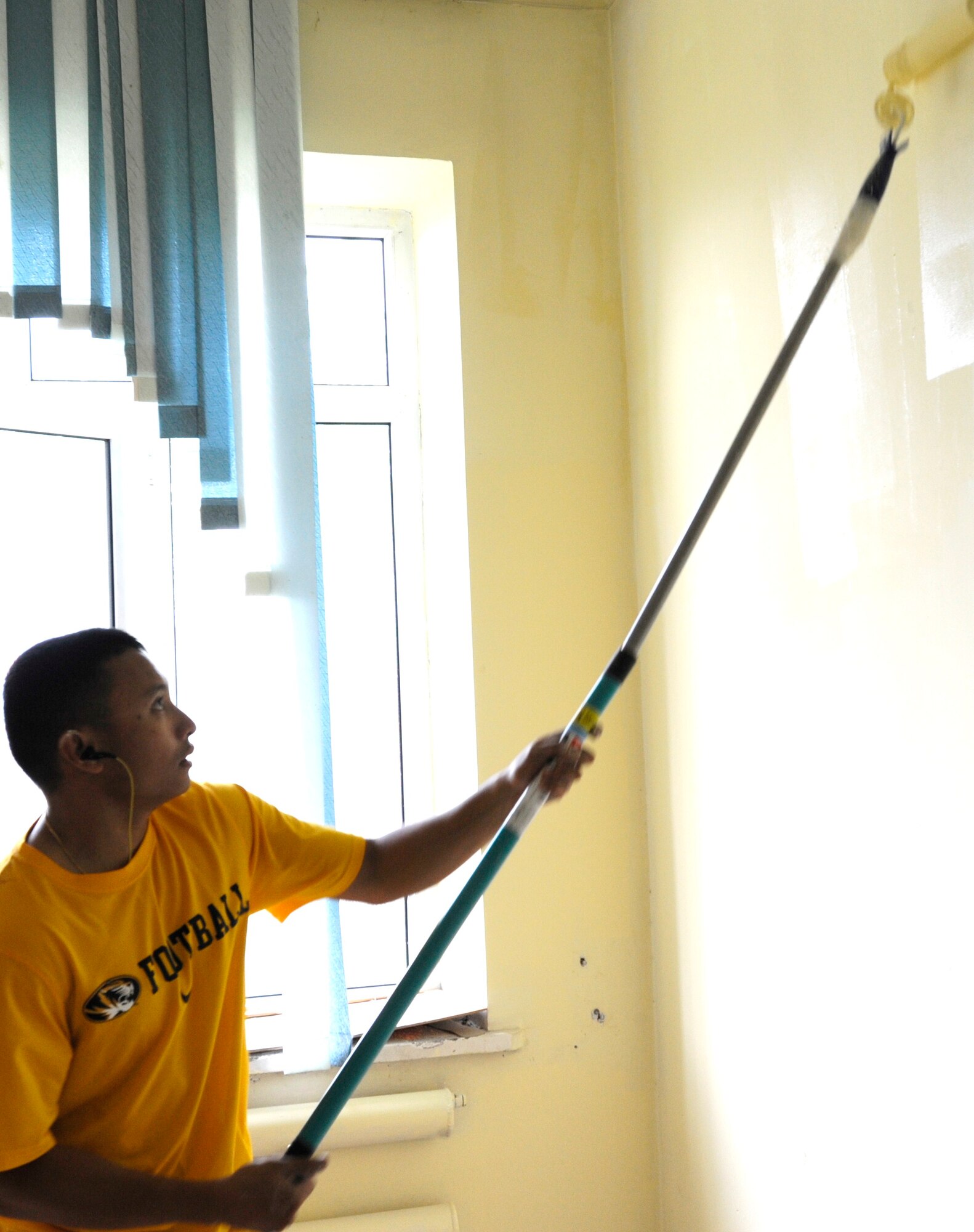Staff Sgt. Ramon Memita paints a wall at the Uventis School for special needs children Aug. 26. Memita is the 376th Air Expeditionary Wing Theater Security Cooperation Humanitarian Assistance Branch project officer. He is deployed to the Transit Center at Manas, Kyrgyzstan, from Yokota Air Base, Japan. (U.S. Air Force photo/Tech. Sgt. Tammie Moore)