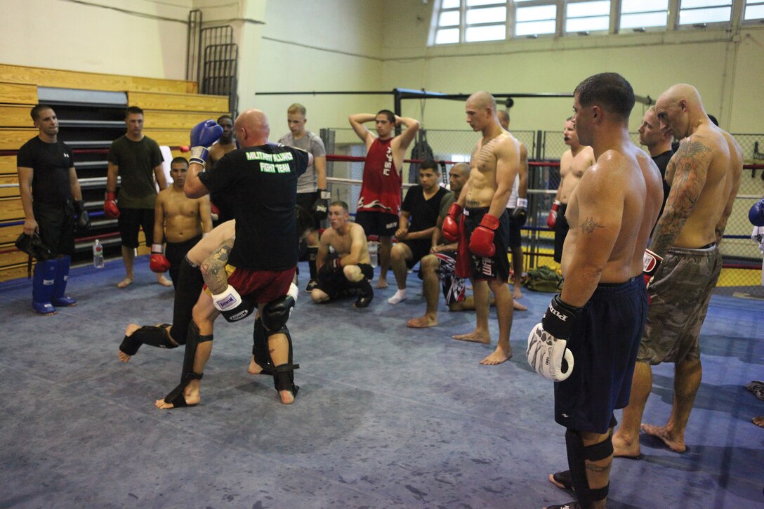 Service members with the Military Alliance Fight Team watch closely as Gunnery Sgt. Christopher J. Kessler instructs them at Camp Foster’s Gunner’s Gym Aug. 30. Kessler is with G-6, Telephone System Branch, Marine Corps Base Camp Butler, and a mixed martial arts coach/tactician.