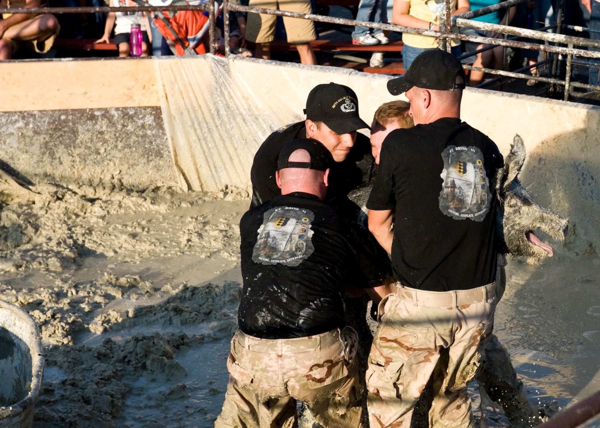 The 28th Civil Engineer Squadron team carries a 160-pound pig towards a trough during a pig wrestling event at the Central States Fair in Rapid City, S.D., Aug. 26, 2011. The team hoped to win money for the Air Force Assistance Fund a fund established to raise funds for charitable affiliates that provide support to Air Force families. (U.S. Air Force photo/Airman Alystria Maurer/Released)