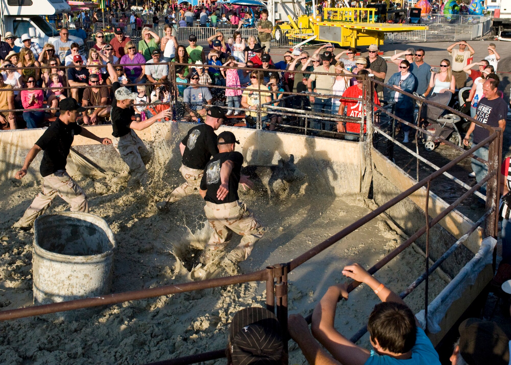Four members of the 28th Civil Engineer Squadron chase a 160-pound pig around a ring during the pig wrestling event at the Central States Fair in Rapid City, S.D., Aug. 26, 2011. After winning the Tuesday night competition, the 28th CES team advanced to the finals on Friday night and placed third overall. (U.S. Air Force photo/Airman Alystria Maurer/Released)