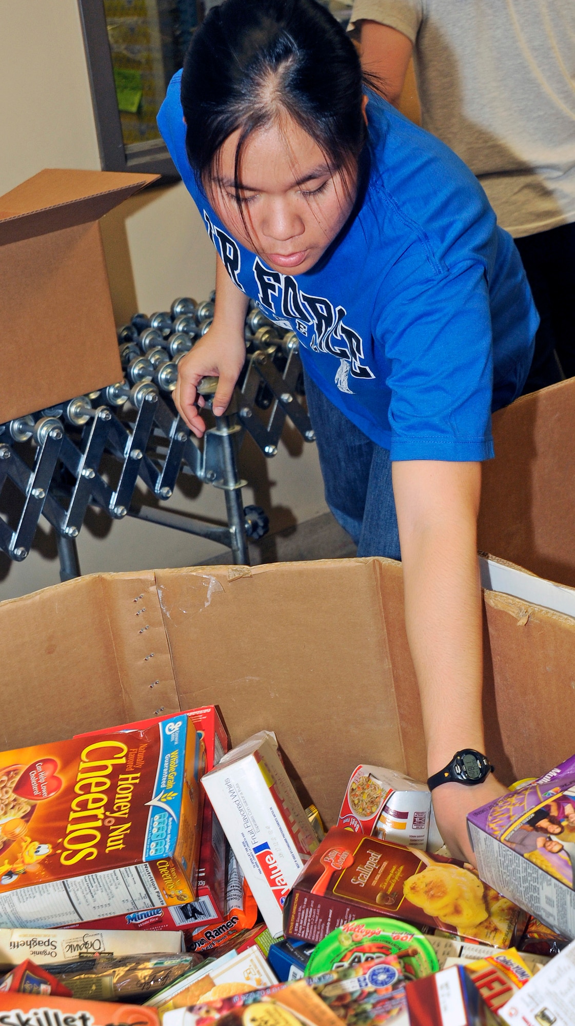 Cadet 2nd Class Jessica Wong gathers boxed goods to prepare a food package during the Air Force Academy Cadet Interfaith Council's volunteer effort at the Care and Share Food Bank of Southern Colorado Aug. 27, 2011. The Interfaith Council began the monthly volunteer project as part of its plan to participate in the White House's Interfaith and Community Service Campus Challenge. Wong, one of the cadets on the Interfaith Council, is assigned to Cadet Squadron 18. (U.S. Air Force photo/Sarah Chambers)