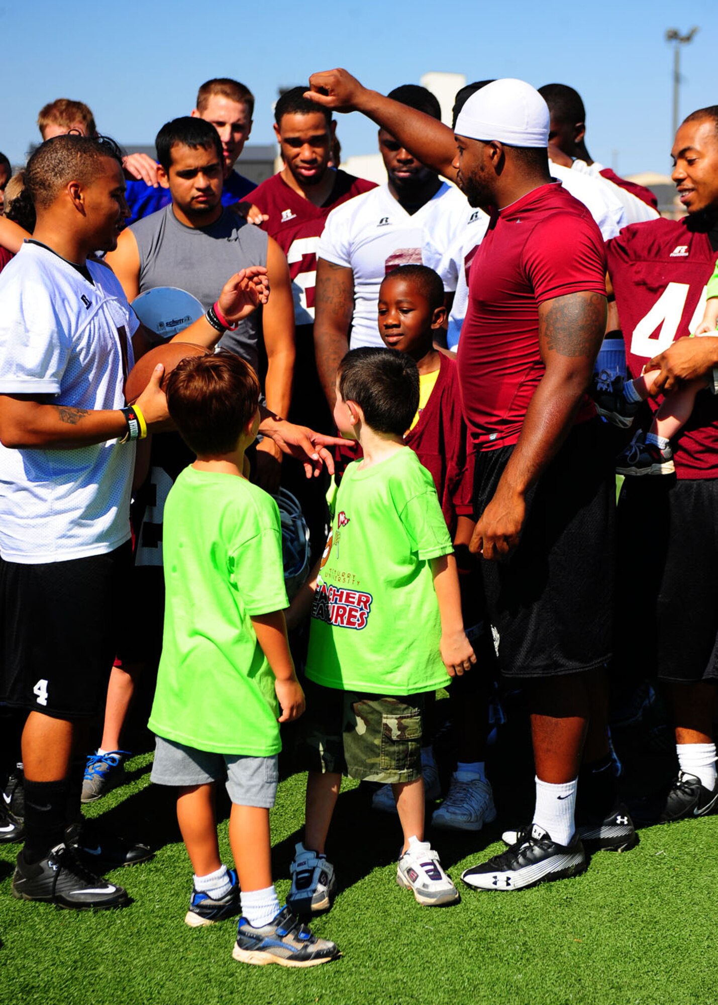 Dyess children and members from the McMurry football team break the huddle Aug. 27 at Dyess Air Force Base, Texas, to mark the end of football camp. The children will be invited to attend all home games to run in front of the team as they enter the football field before the game. They also have a program called Maroon pride, which is a program where the local community buy football tickets and donate them to the base. (U.S. Air Force photo by Senior Airman Chelsea Browning/Released)